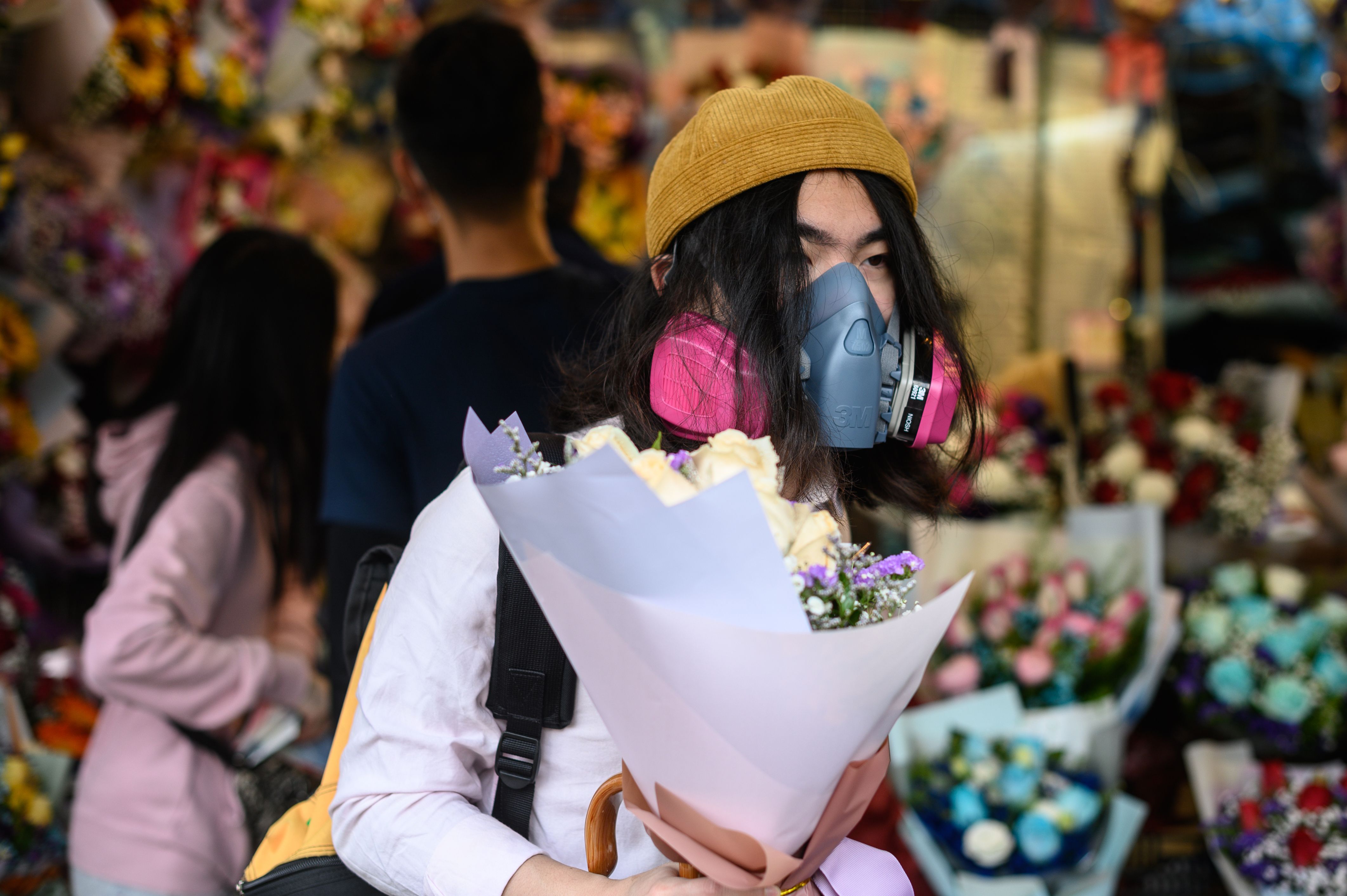 Seorang pria mengenakan masker saat membeli bunga untuk Valentine di Hong Kong.