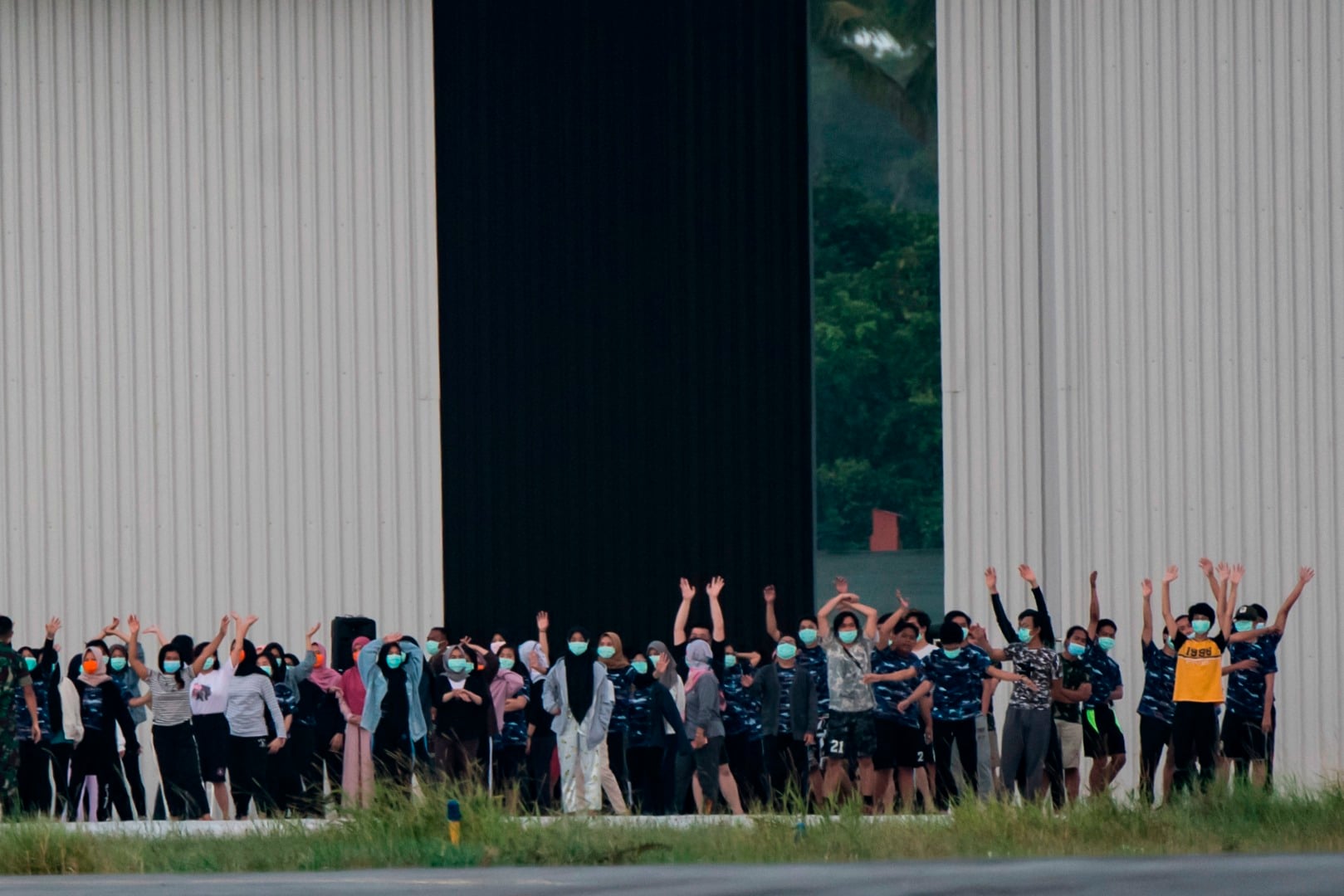 Sejumlah WNI yang dievakuasi dari Wuhan, Hubei, Tiongkok melambaikan tangan kearah media saat akan melakukan senam di Natuna.