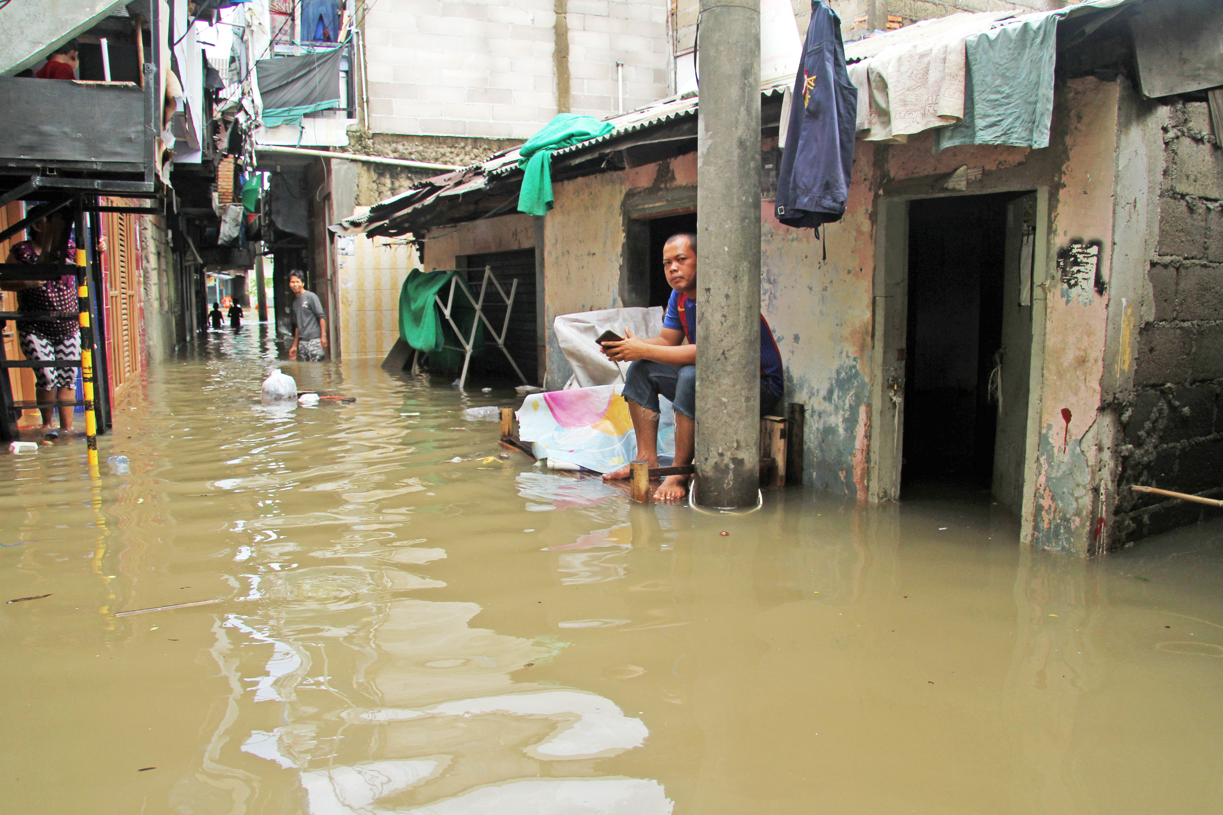 Warga beraktivitas di kawasan permukiman penduduk yang tergenang banjir, di Kampung Petukangan, Cakung