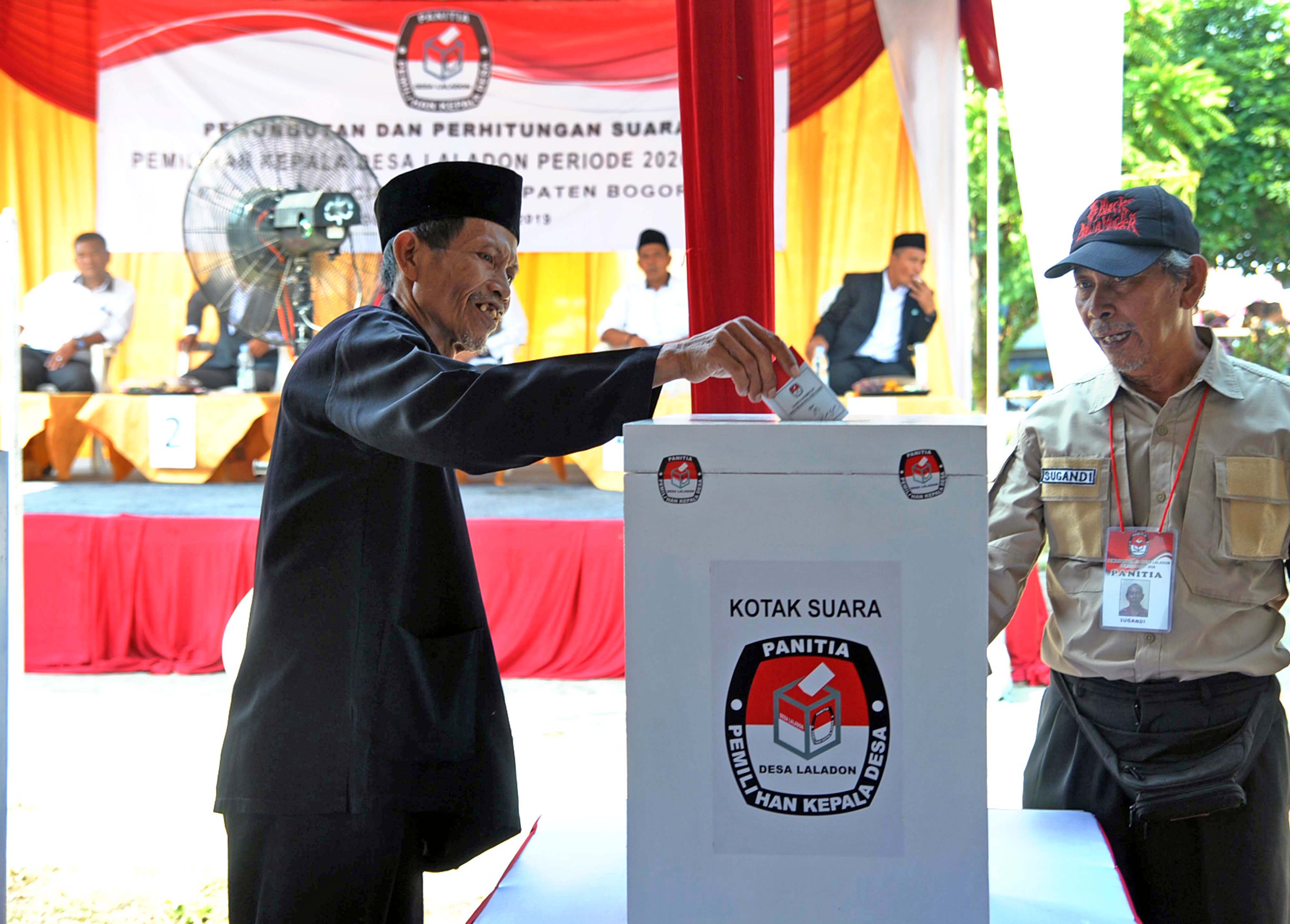 Warga memasukkan surat suara kedalam kotak suara dalam Pemilihan Kepala Desa (Pilkades) Laladon Tahun 2019.