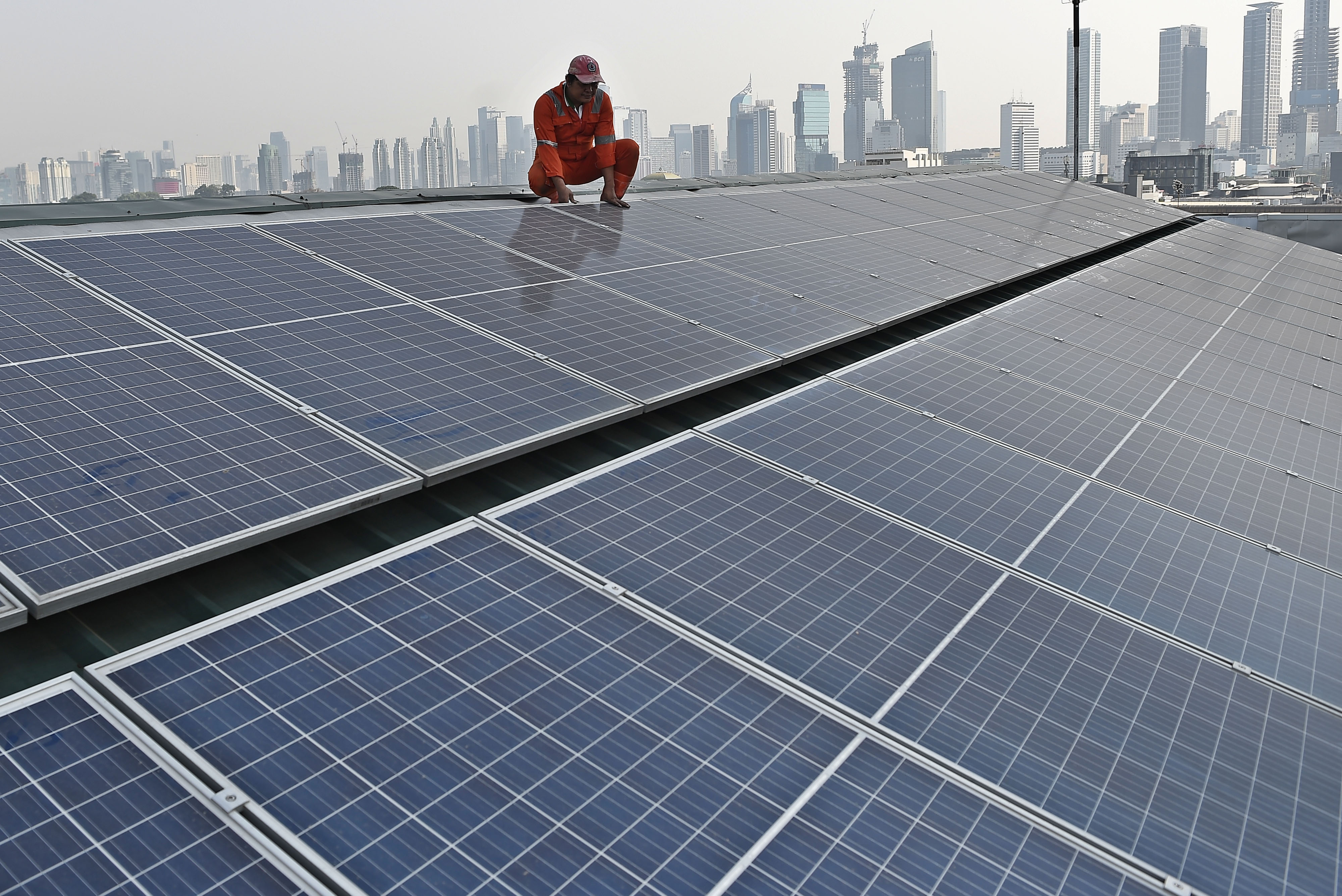 Petugas melakukan perawatan panel surya di atap.