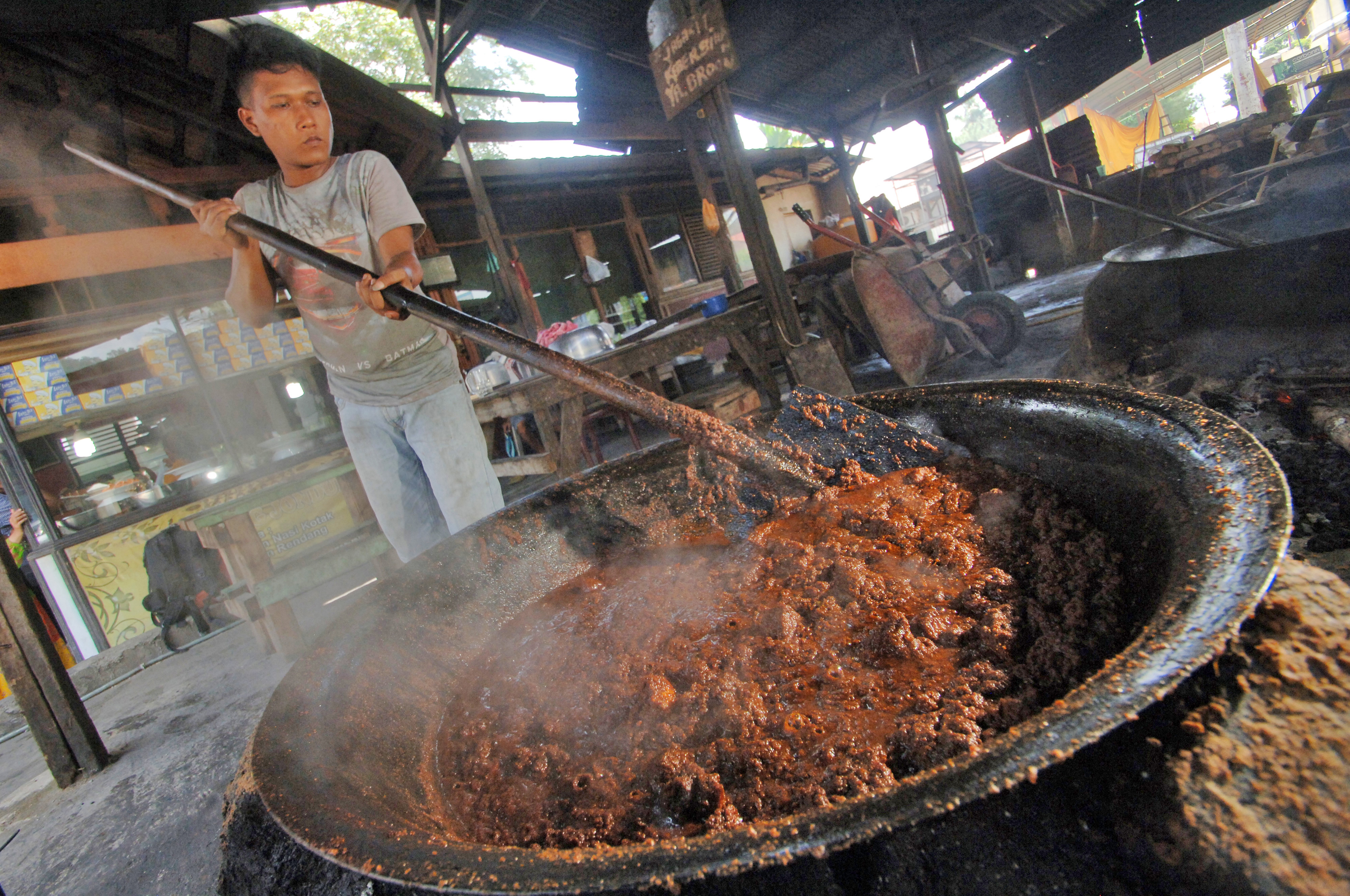 Mengolah daging sapi menjadi rendang.
