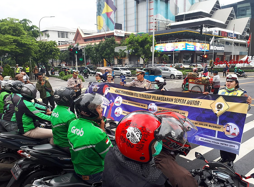 Polisi lalu lintas melakukan sosialisasi penerapan  tilang elektronik ke pengendara sepeda motor di Jalan MH Thamrin, Jakarta