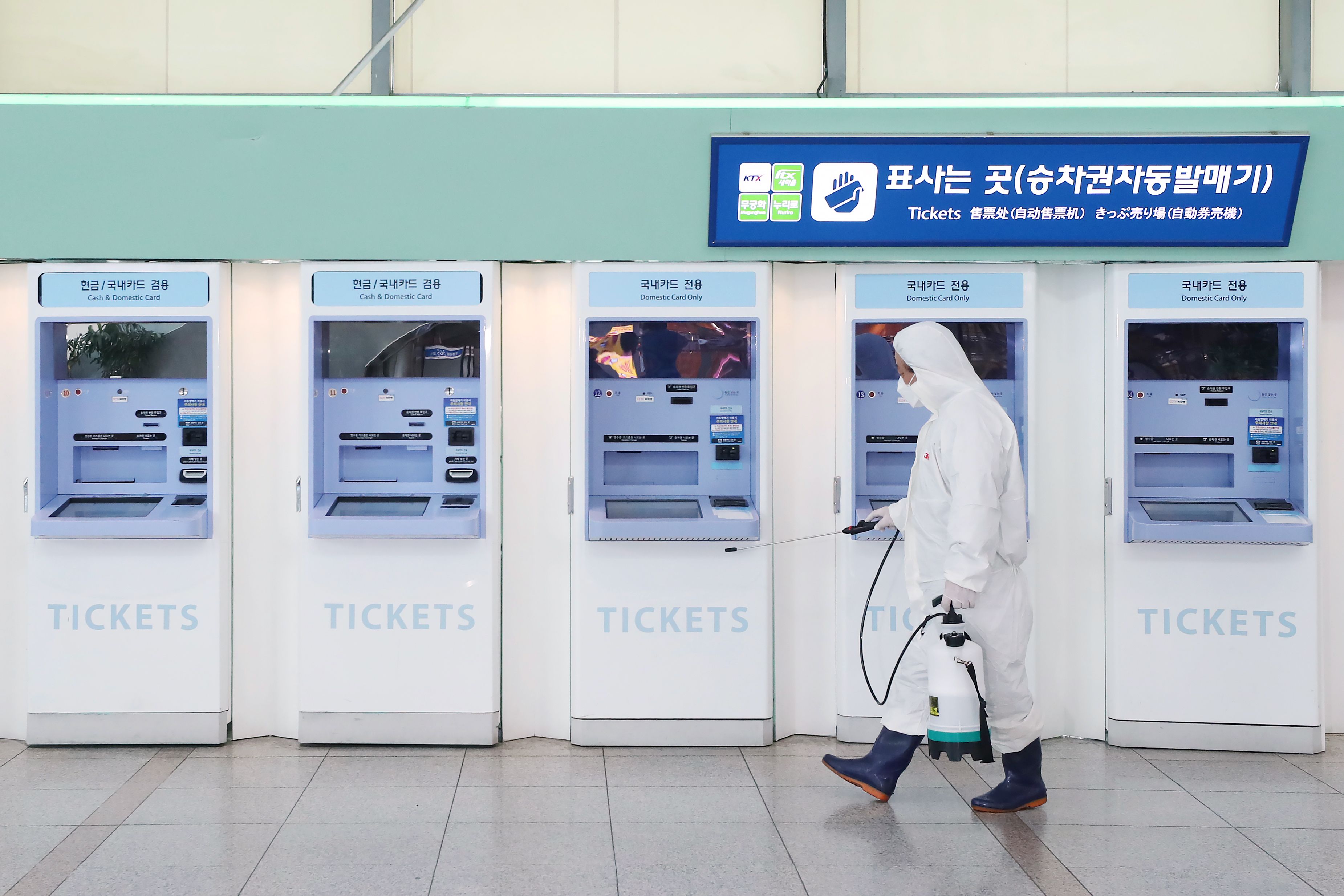 Petugas yang mengenakan pakaian pelindung menyemprotkan disinfektan di sebuah stasiun kereta di Seoul, Korea Selatan.