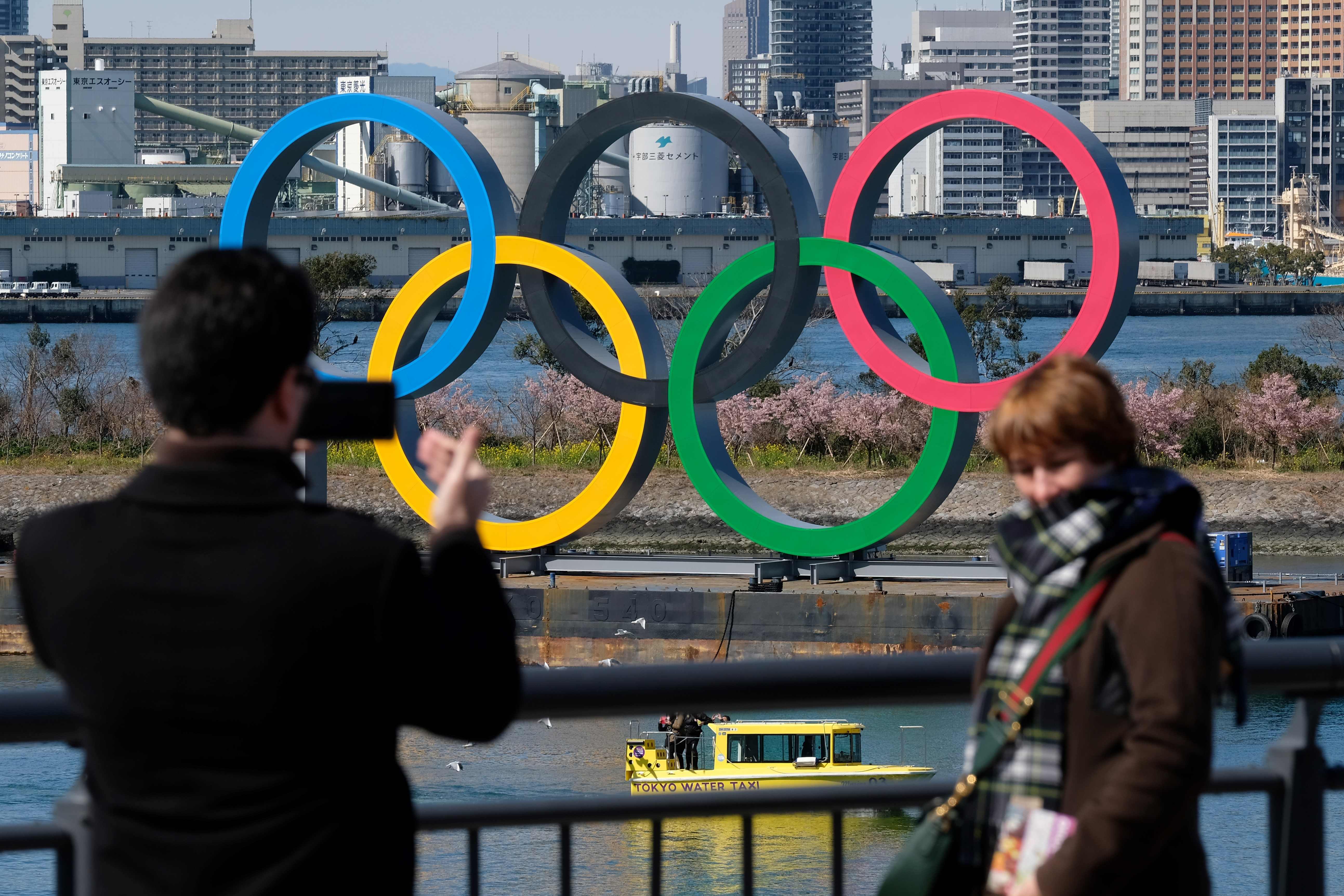Seorang wisawatan berpose di depan logo Olimpiade yang dipasang di Odaiba Marine Park, Tokyo.