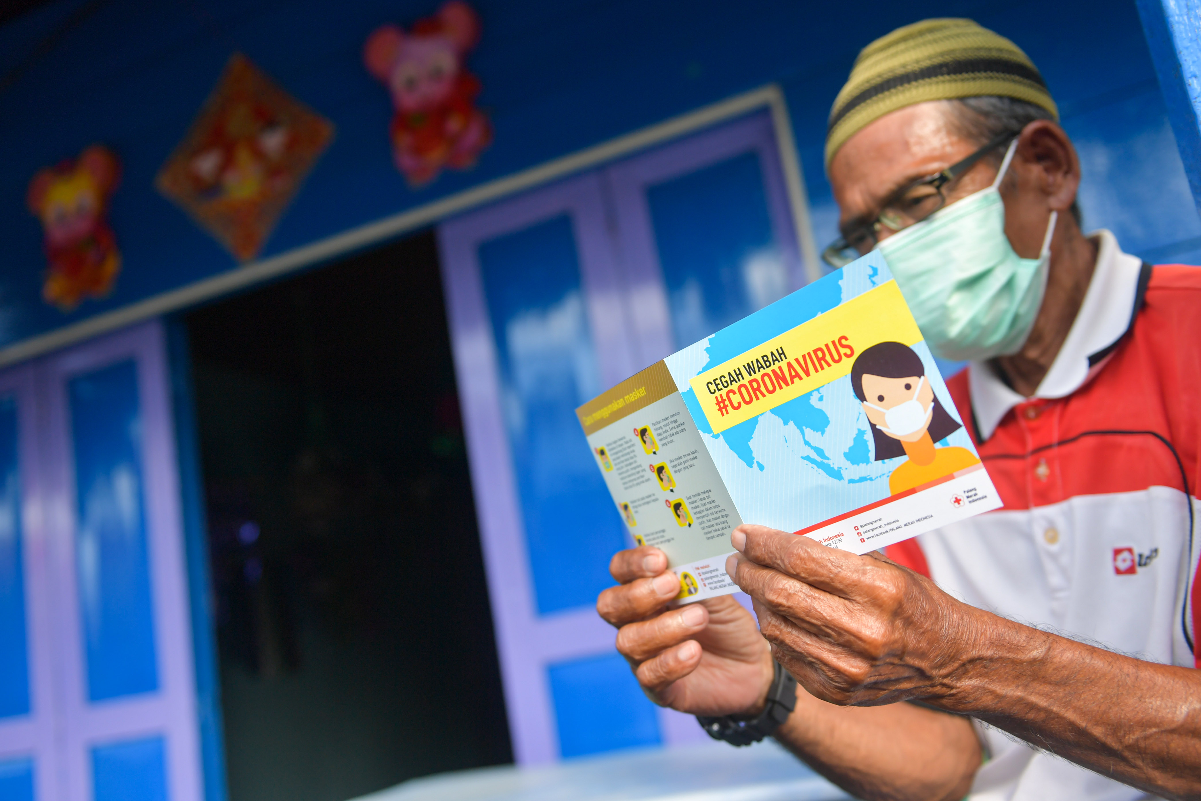 Warga menggunakan masker saat membawa informasi soal virus korona