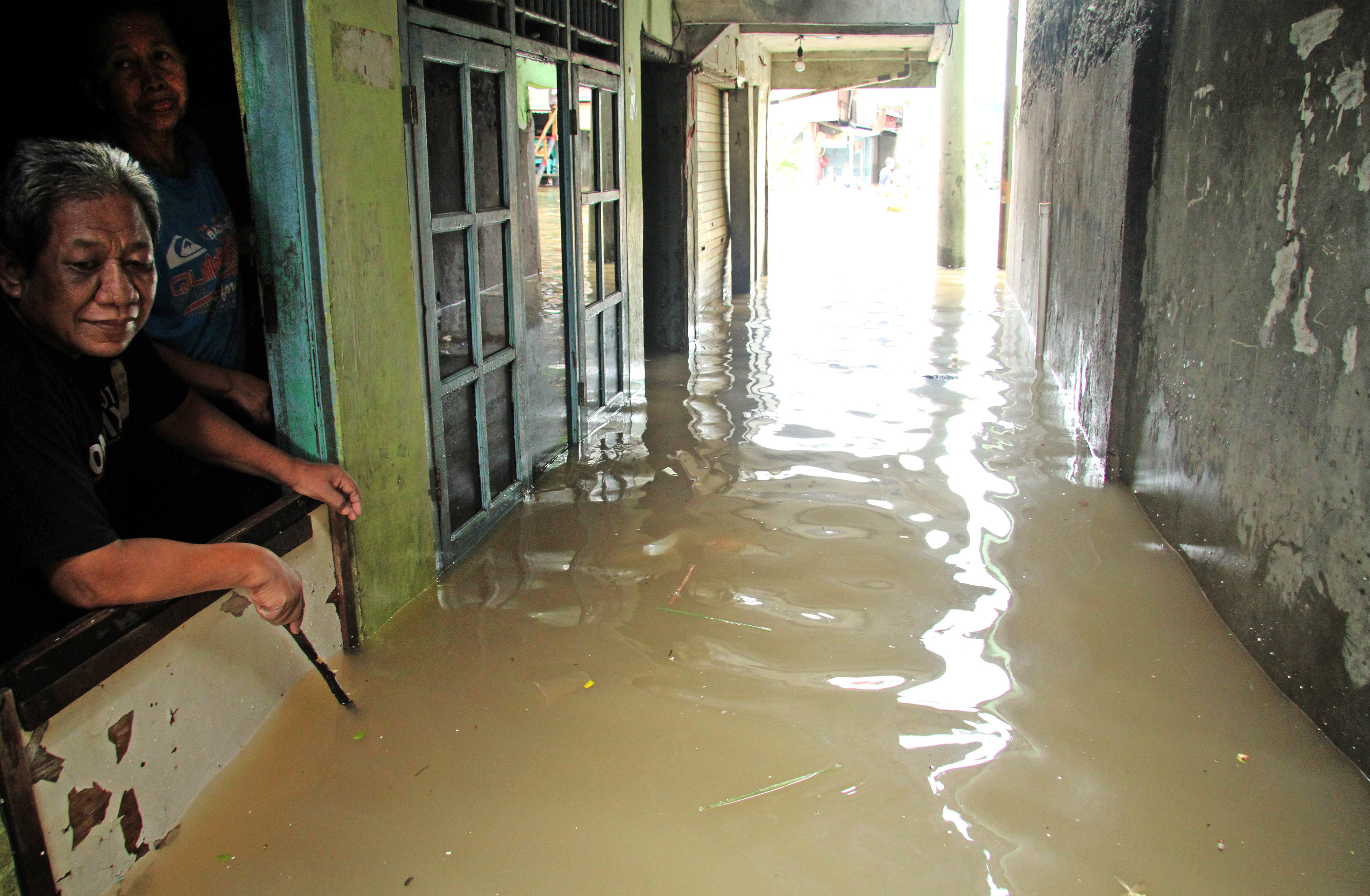 Warga beraktivitas di kawasan permukiman penduduk yang tergenang banjir, di Kampung Petukangan, Cakung, Jakarta.