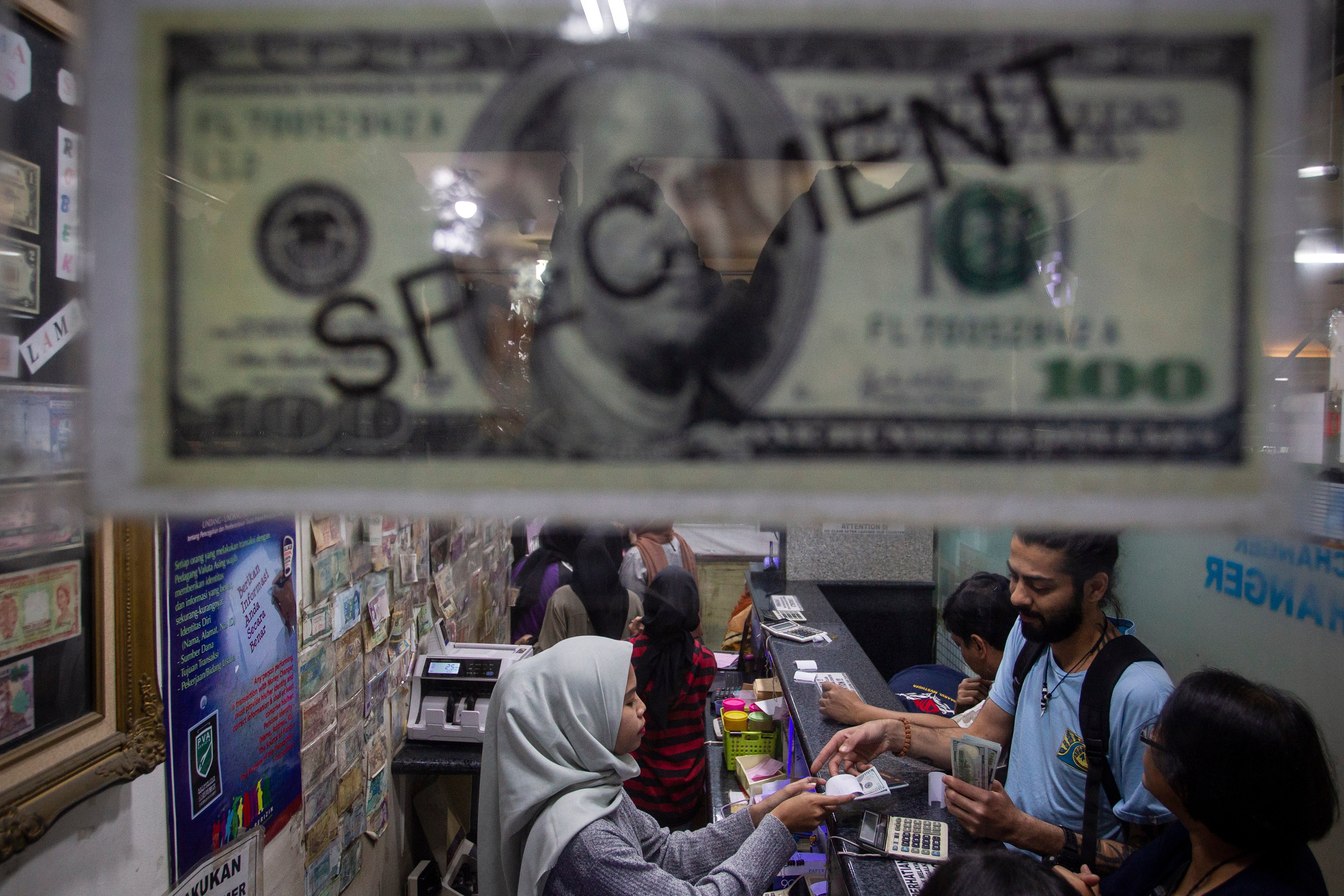 Aktivitas warga saat menukarkan uang di salah satu gerai penukaran mata uang asing di Jakarta.