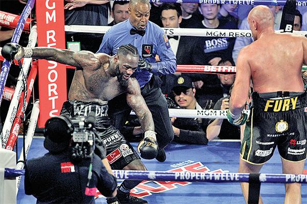 Petinju Amerika Serikat, Deontay Wilder (kiri), terduduk setelah dihujani pukulan oleh lawannya, petinju Inggris, Tyson Fury