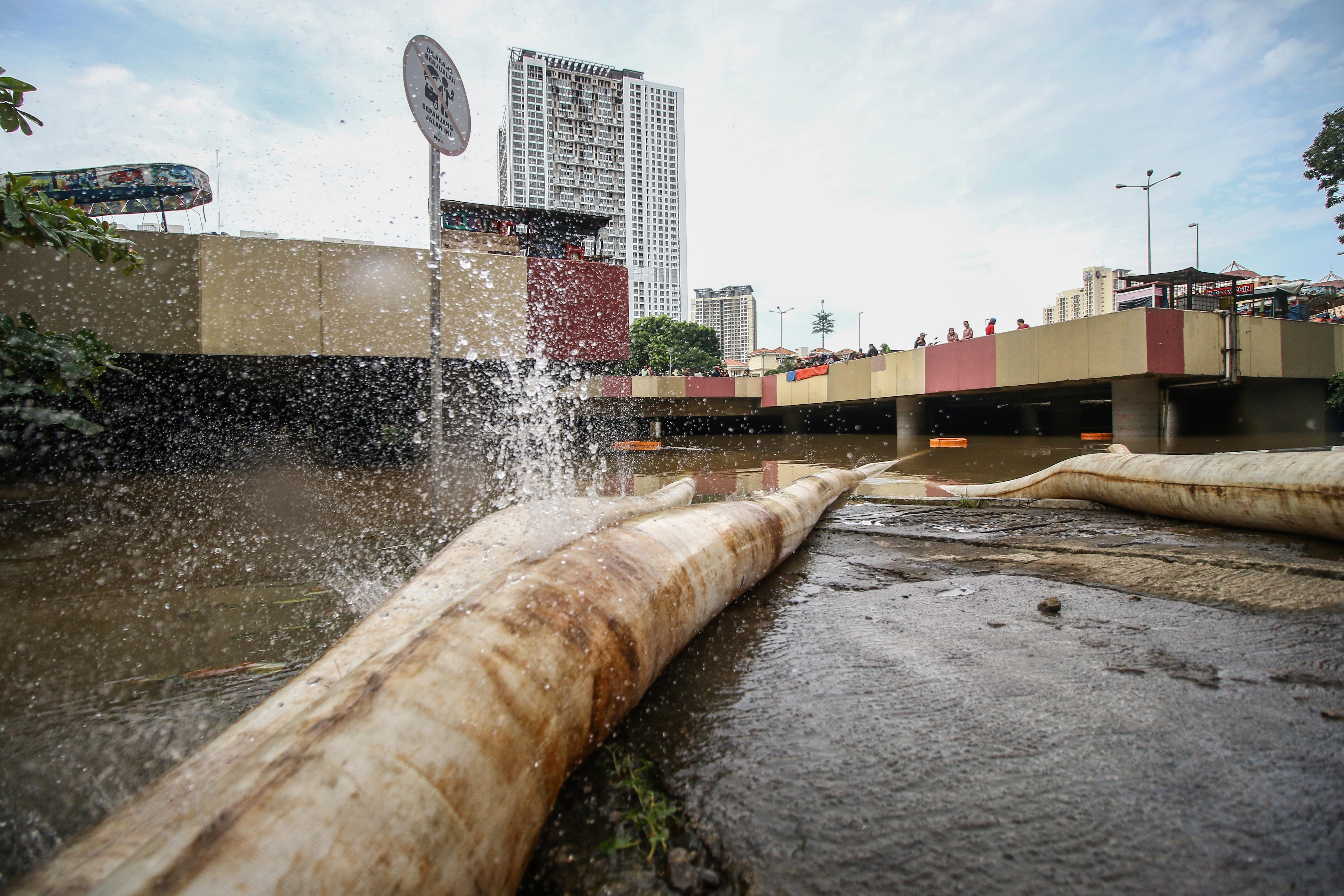 Selang air memompa banjir yang menutup Underpass Kemayoran, Jakarta, Minggu (2/2/2020).