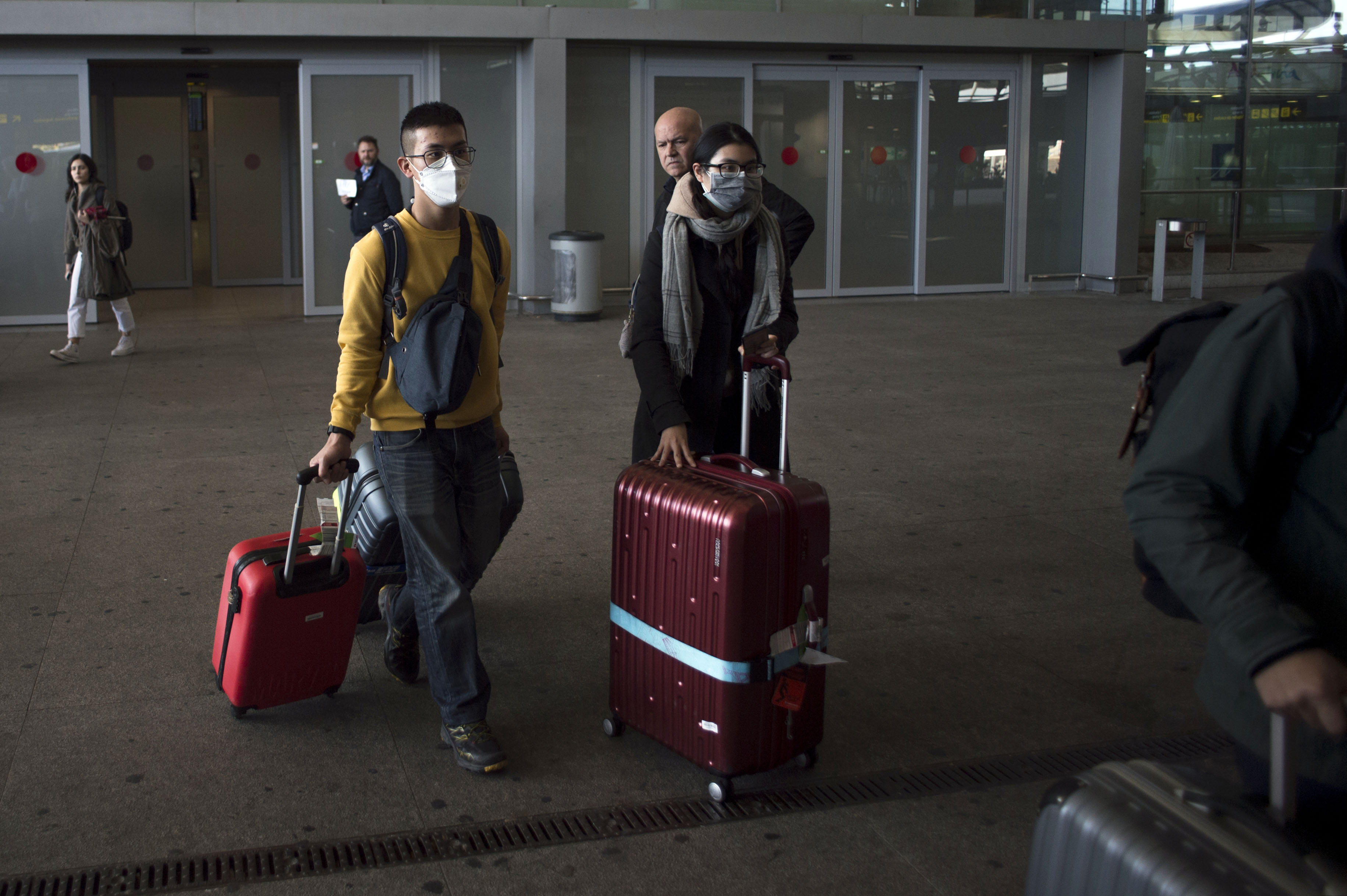 Dua penumpang mengenakan masker saat tiba di Bandara Costa del Sol, Malaga, Spanyol.