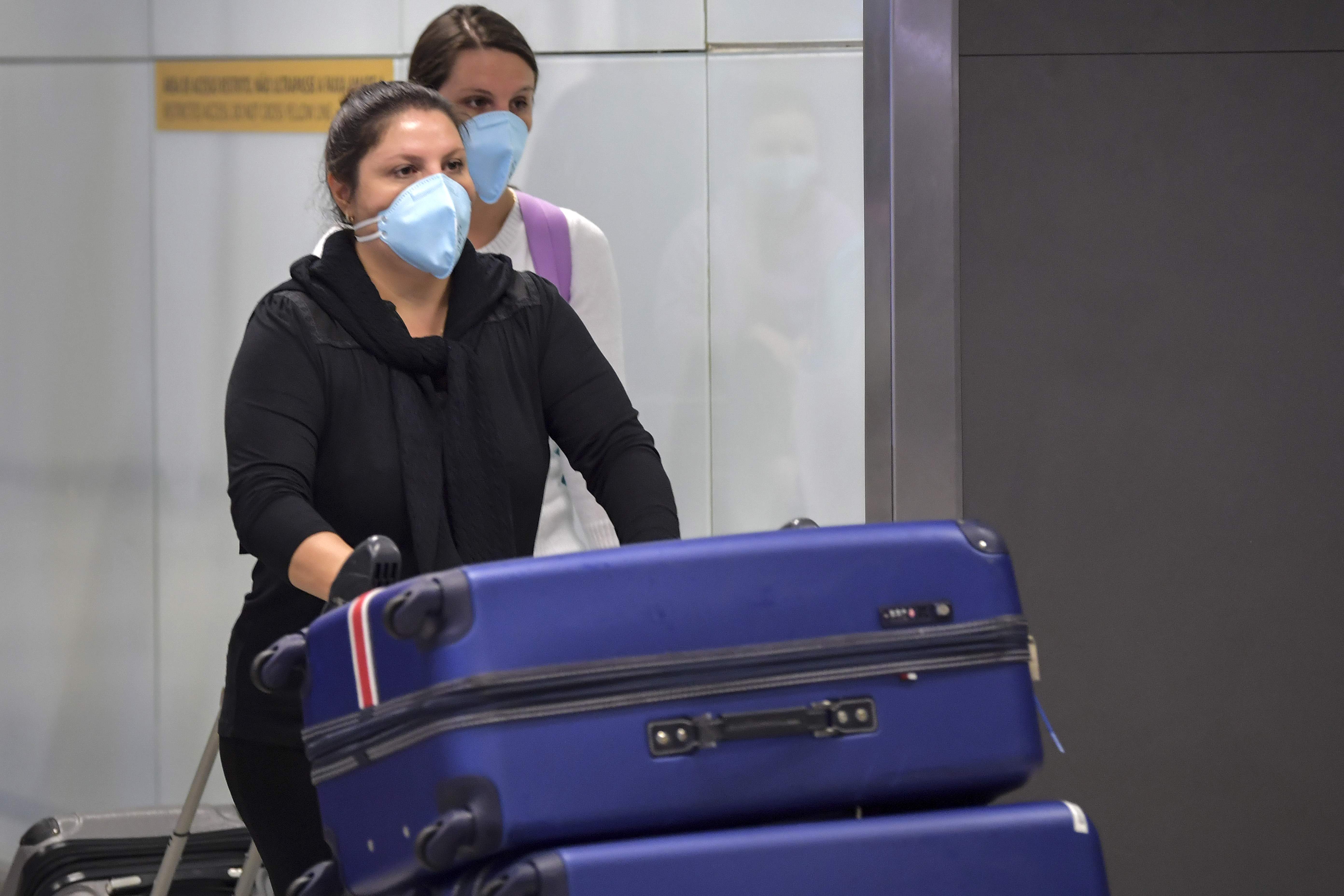 Warga Brasil menggunakan masker untuk menangkal penularan virus korona di Bandara Guarulhos, Sao Paolo