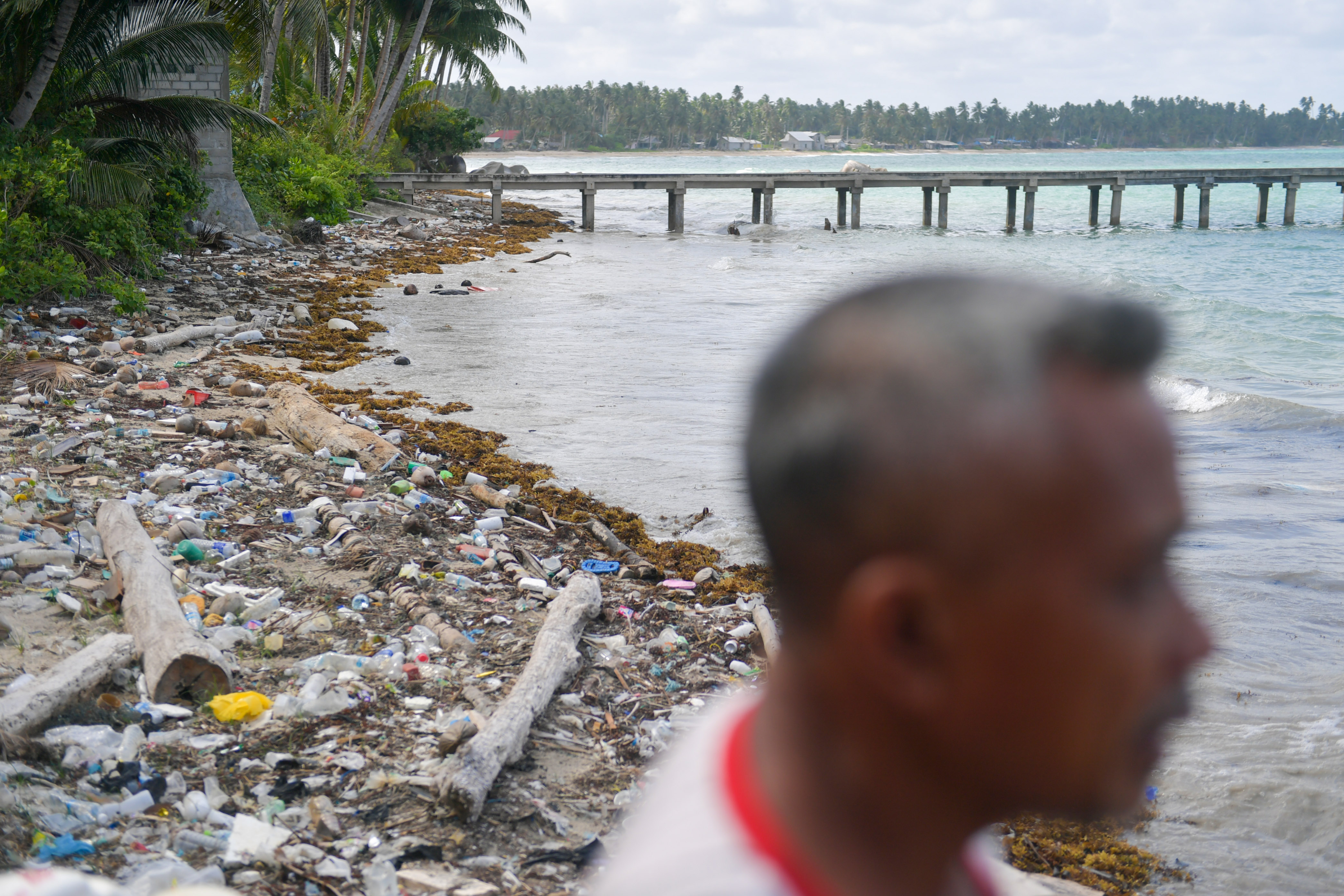 Seorang warga berada tak jauh dari hamparan sampah botol plastik yang terdampar di pesisir pantai Sepempang, Natuna, Kepulauan Riau.