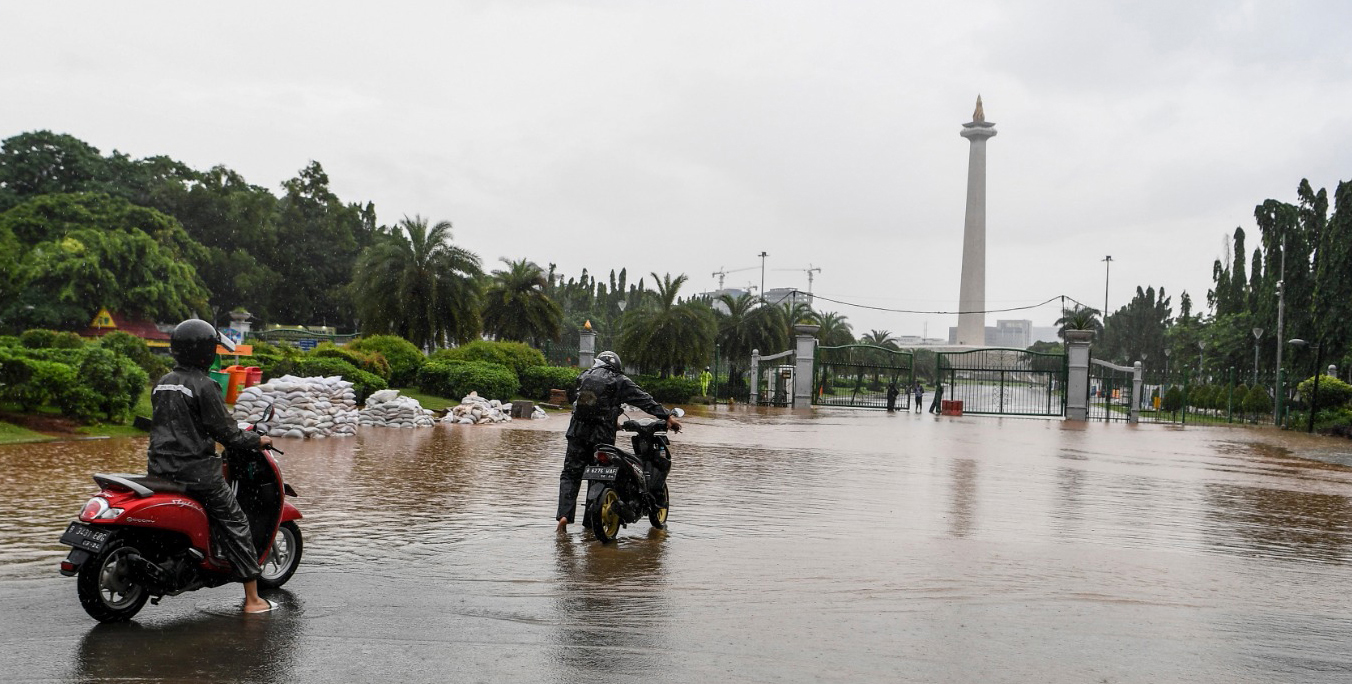 Warga mendorong motor melintasi banjir di kawasan Monas, Jalan Medan Merdeka Barat, Jakarta, Minggu (2/2/2020). 