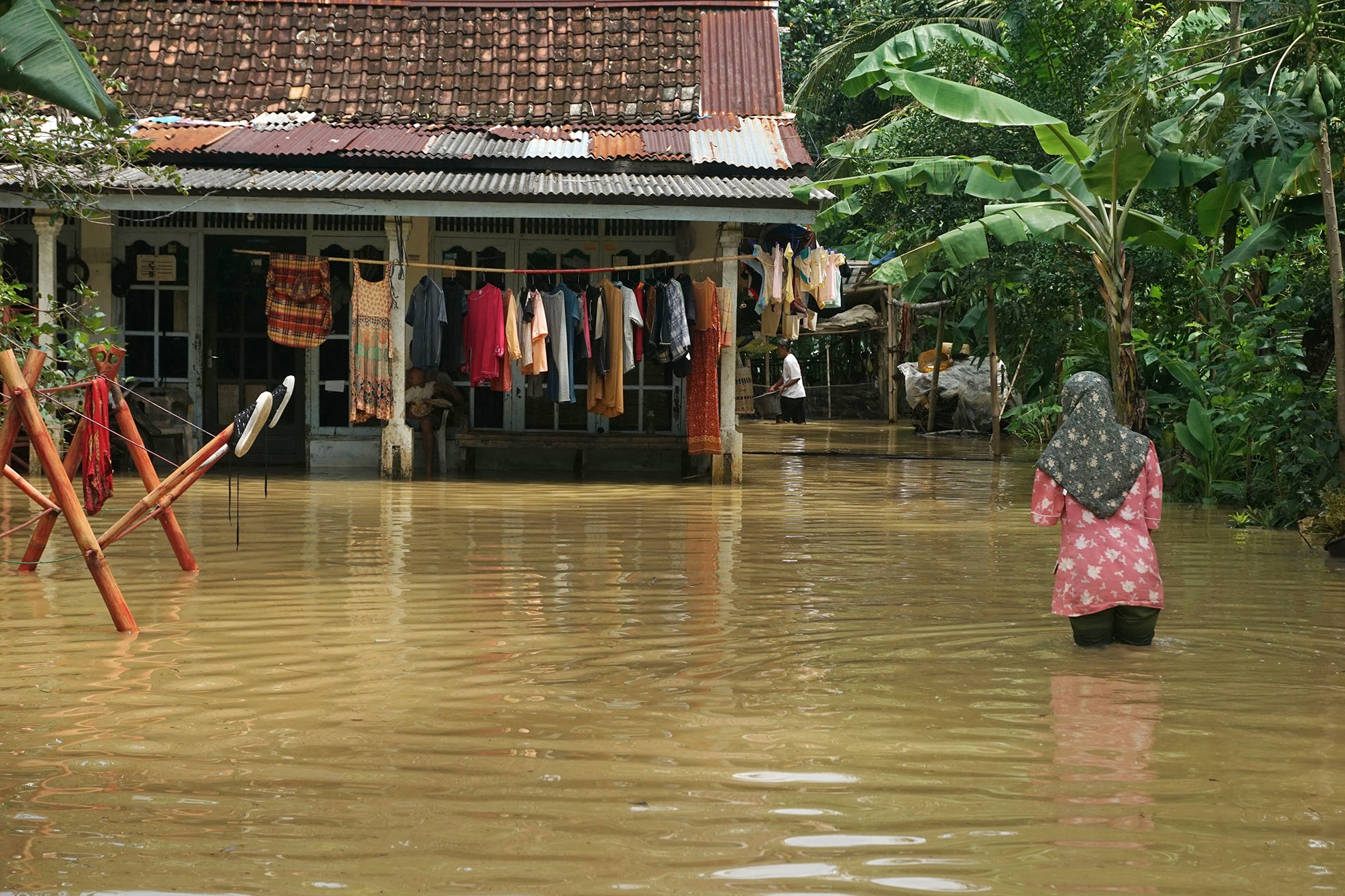 Warga berjalan di tengah banjir yang merendam permukiman penduduk di Desa Mujur Lor, Kroya, Cilacap, Jateng.