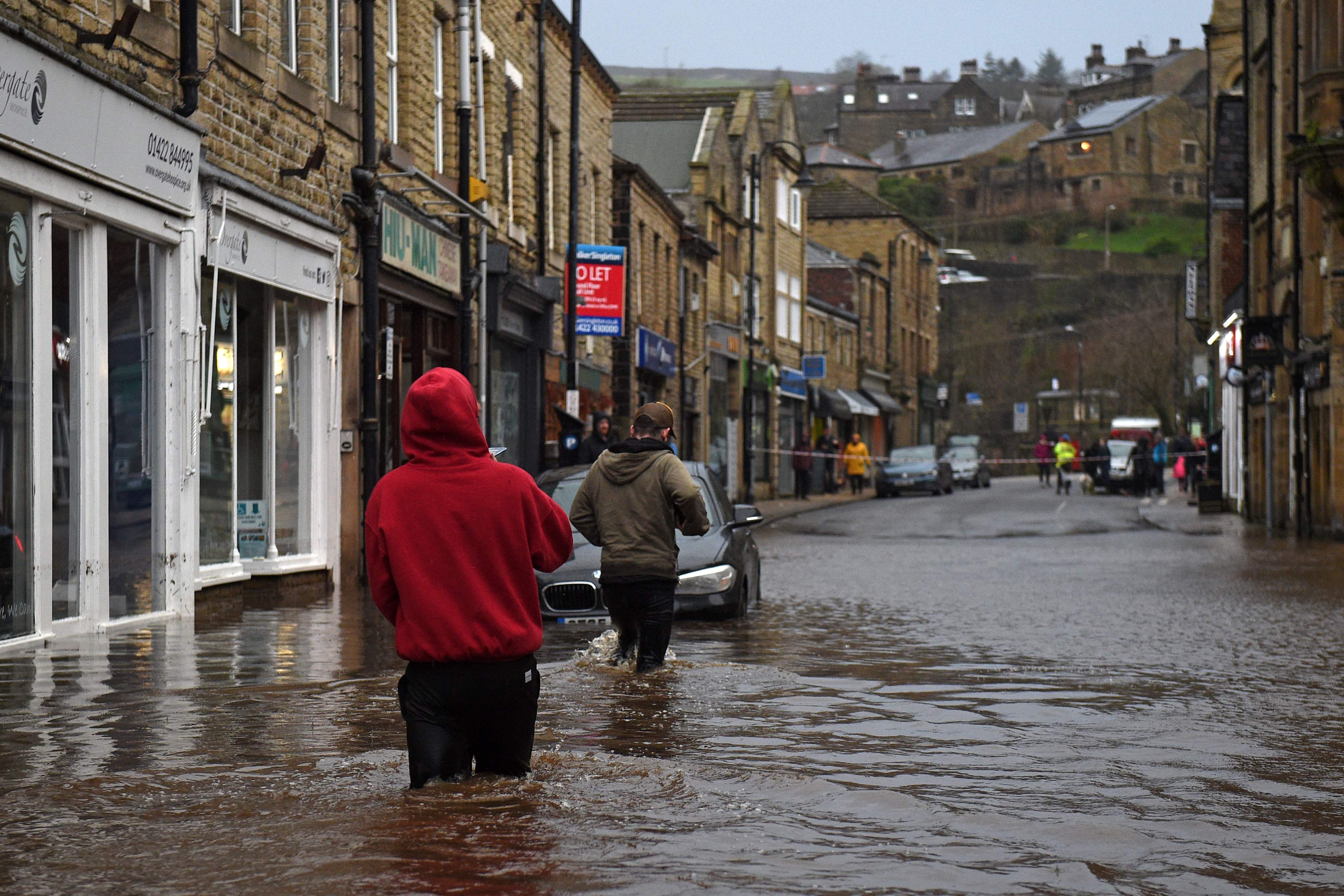 Sejumlah warga berjalan di Kota Hebden Bridge, Inggris yang dilanda banjir akibat Badai Ciara.