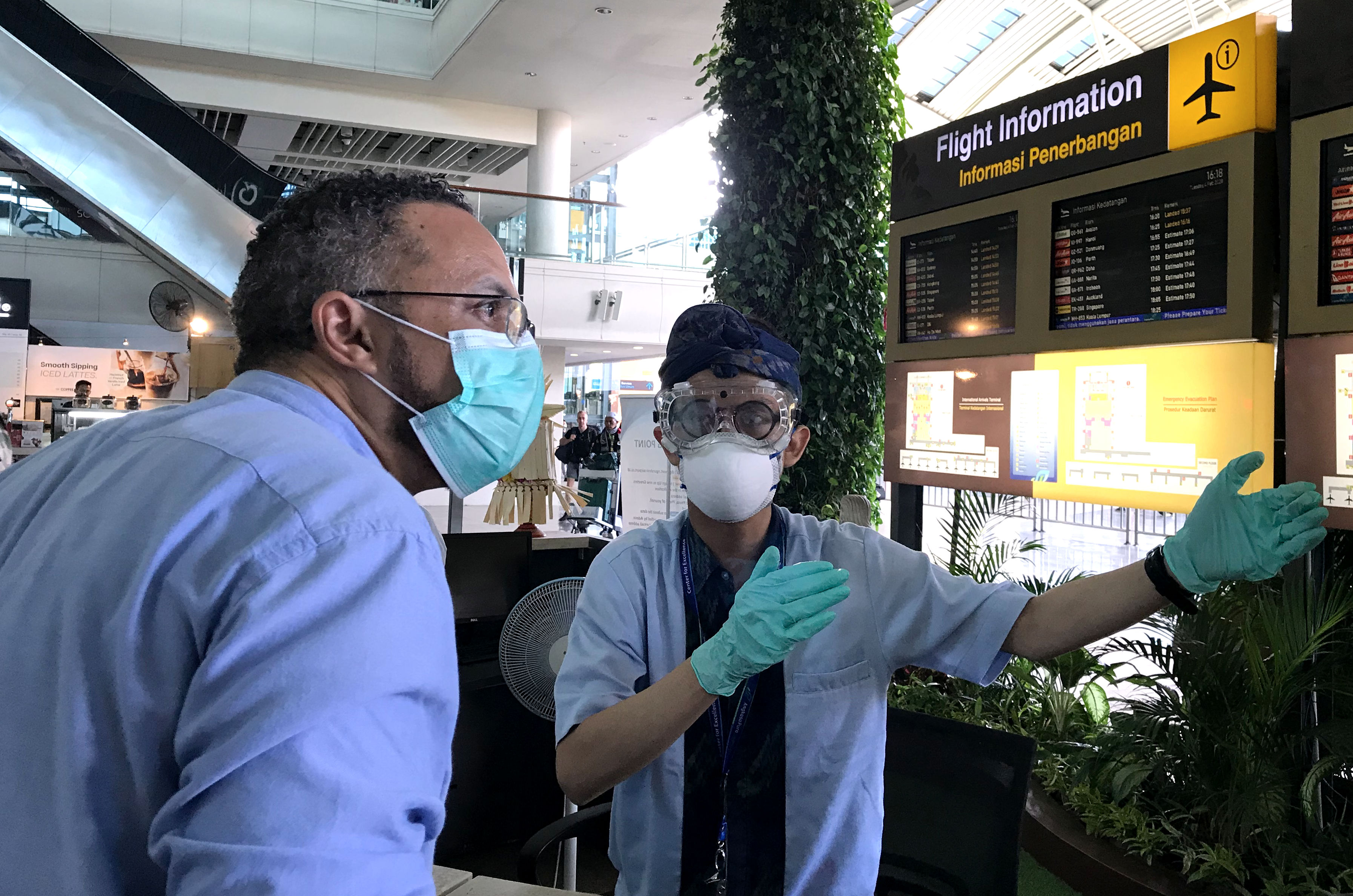 Petugas mengenakan alat pelindung memberikan informasi di Terminal Kedatangan Internasional Bandara Internasional I Gusti Ngurah Rai