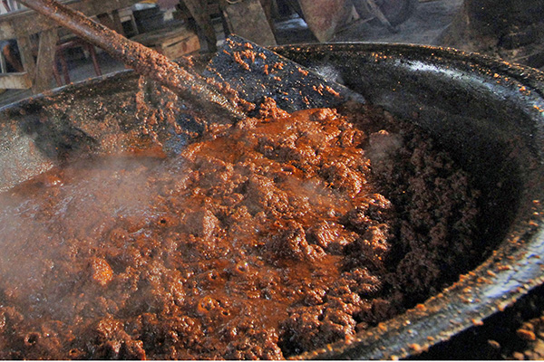 Seorang pekerja mengeringkan rendang daging sapi yang dimasak menggunakan tungku, di rumah randang Rajo-rajo, di Padang, Sumatera Barat