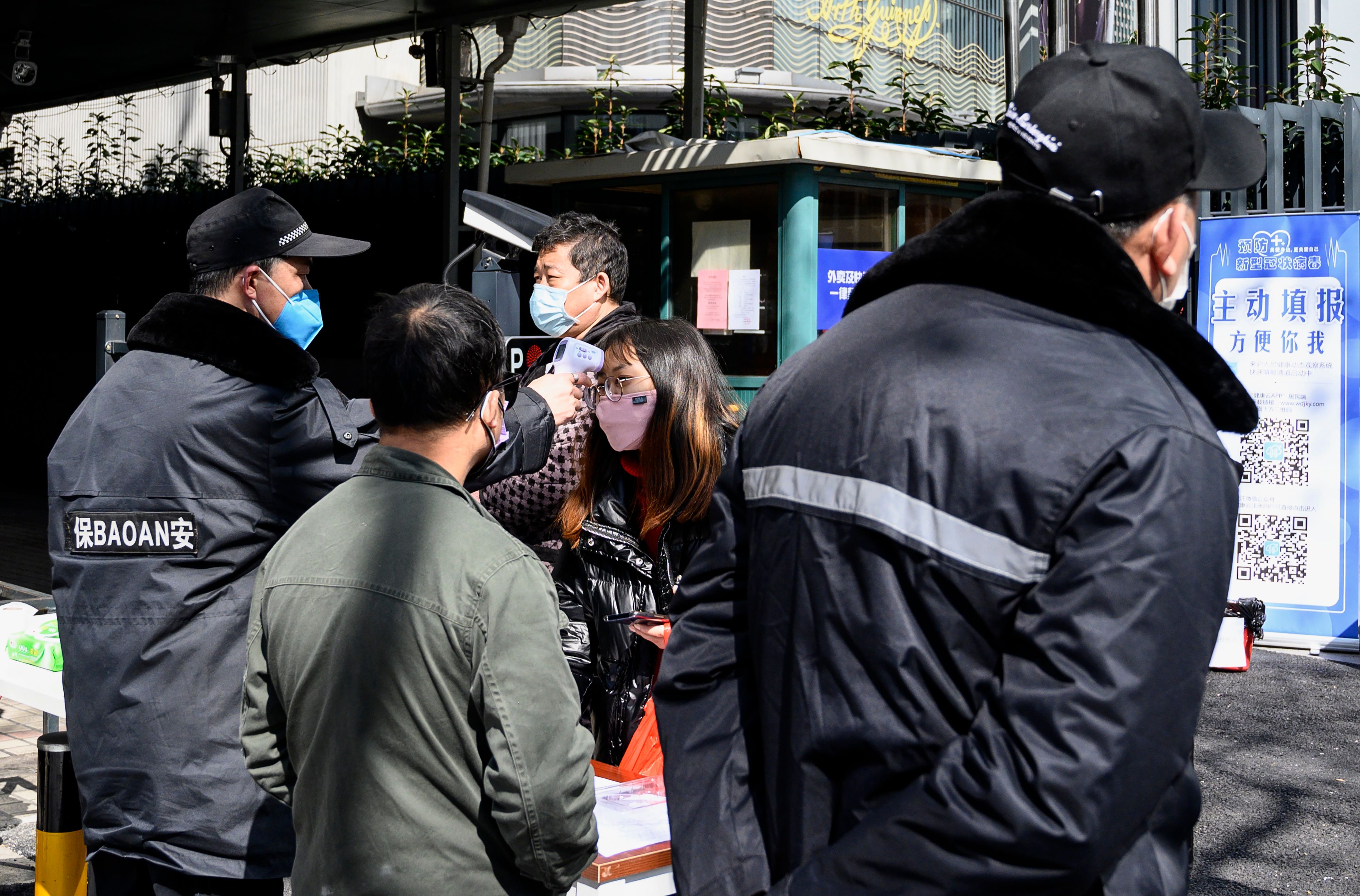 Seorang petugas keamanan memeriksa suhu tubuh orang yang akan masuk ke dalam komplek perumahan di Shanghai, Tiongkok