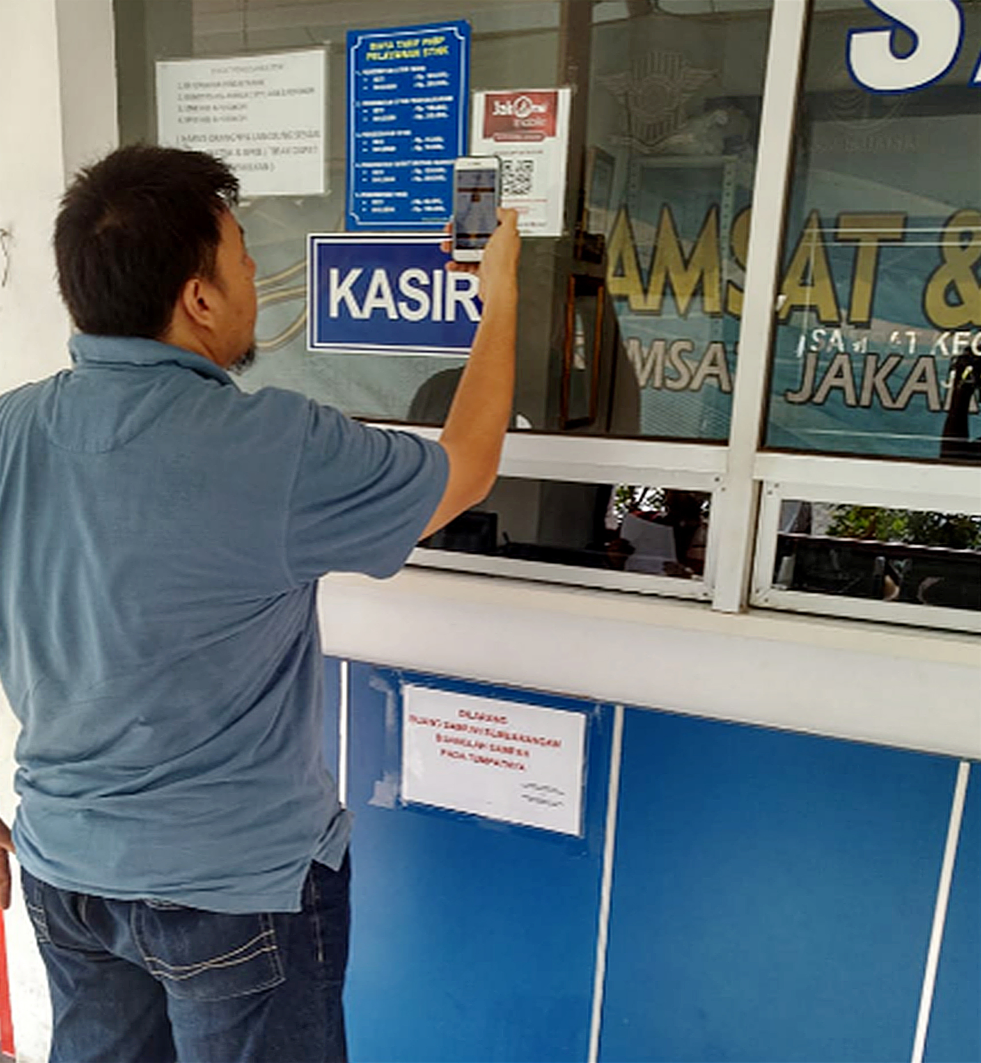 Seorang wajib pajak melakukan transaksi pembayaran pajak kendaraan bermotor (PKB) menggunakan JakOne Mobile di Samsat DKI.