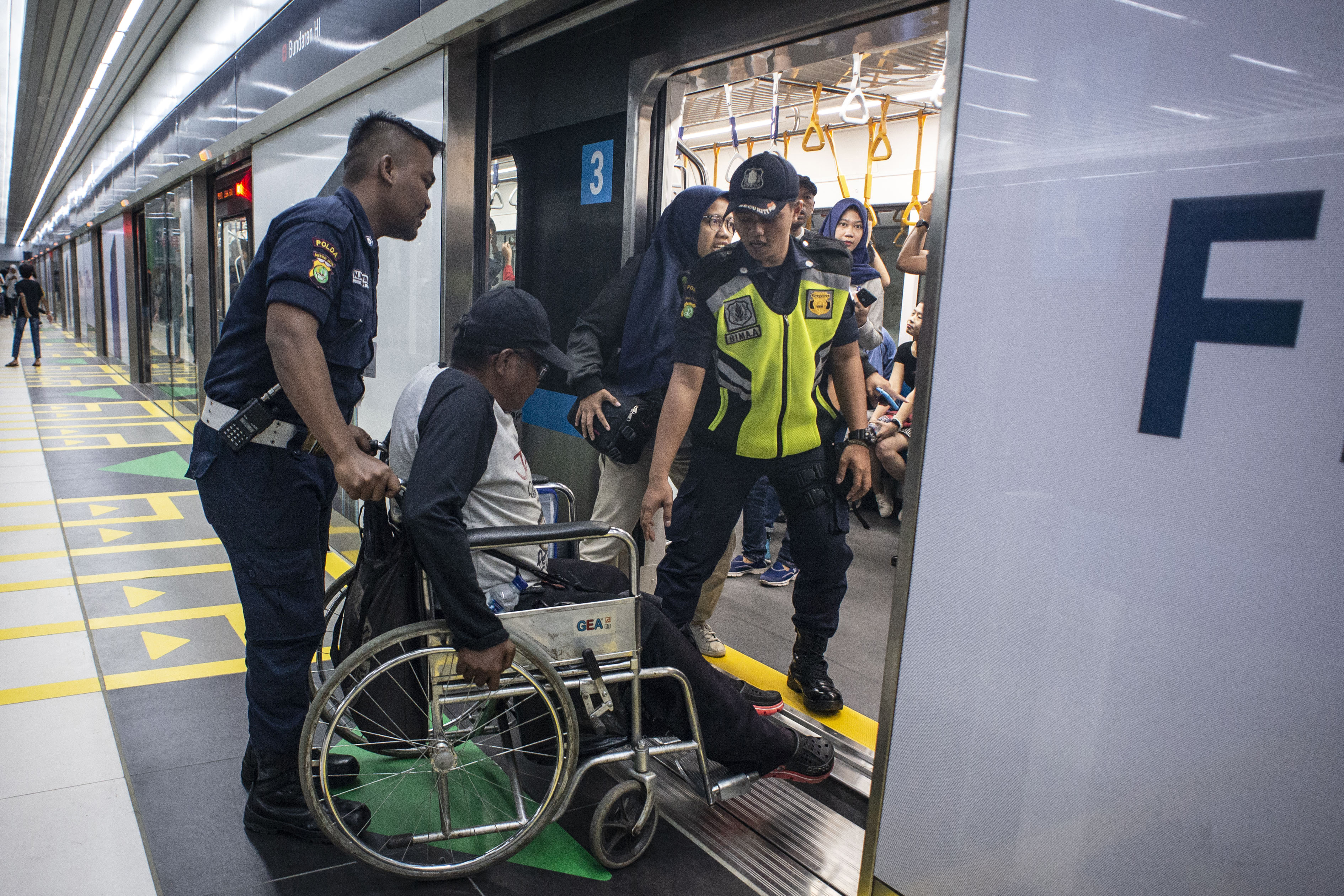 Petugas membantu seorang penyandang disabilitas naik ke kereta MRT di Stasiun MRT Bundaran HI, Jakarta, Minggu (24/3/2019).