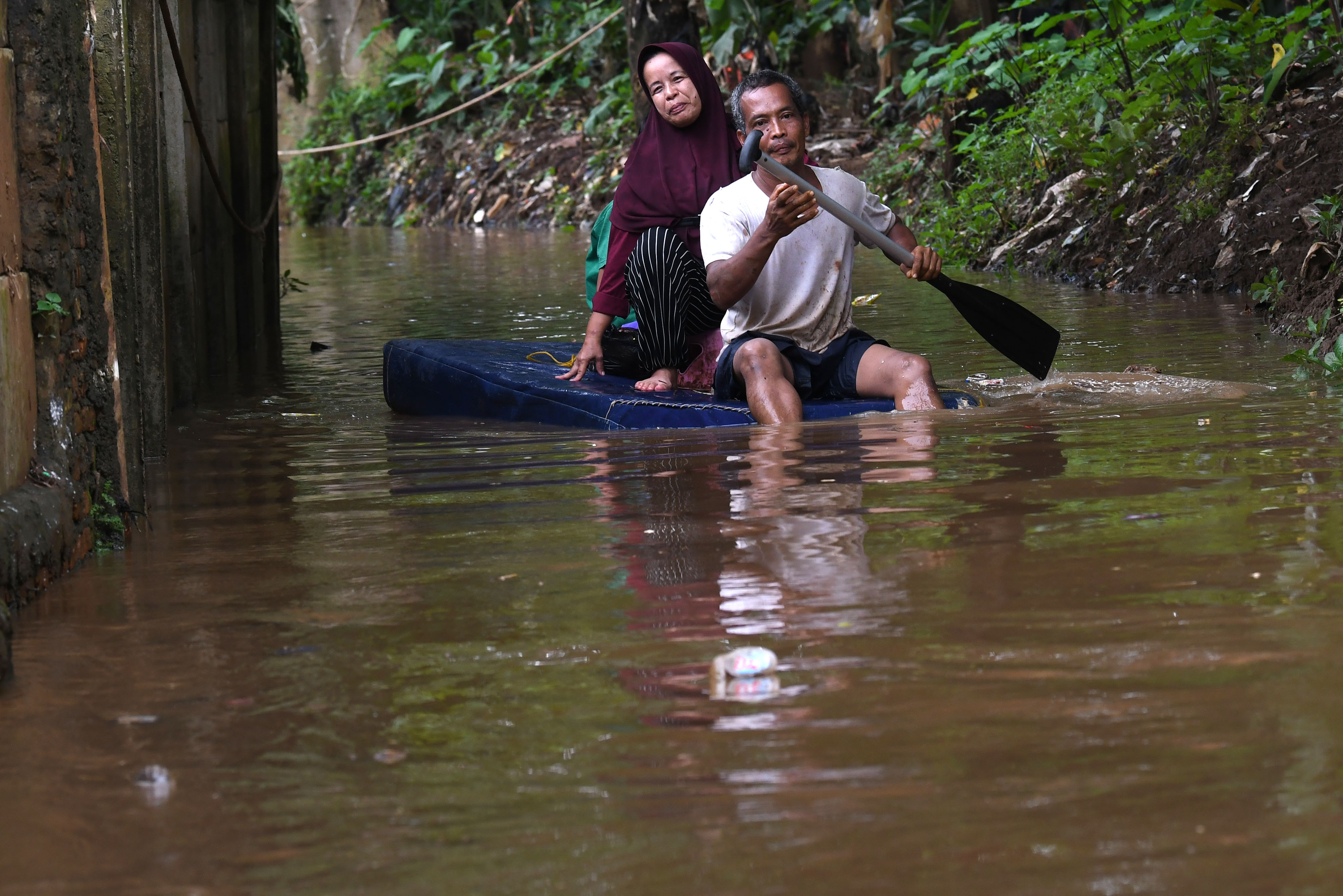 Warga menggunakan perahu buatannya untuk menyusuri jalan perkampungan yang tergenang banjir luapan air Sungai Ciliwung di Cawang