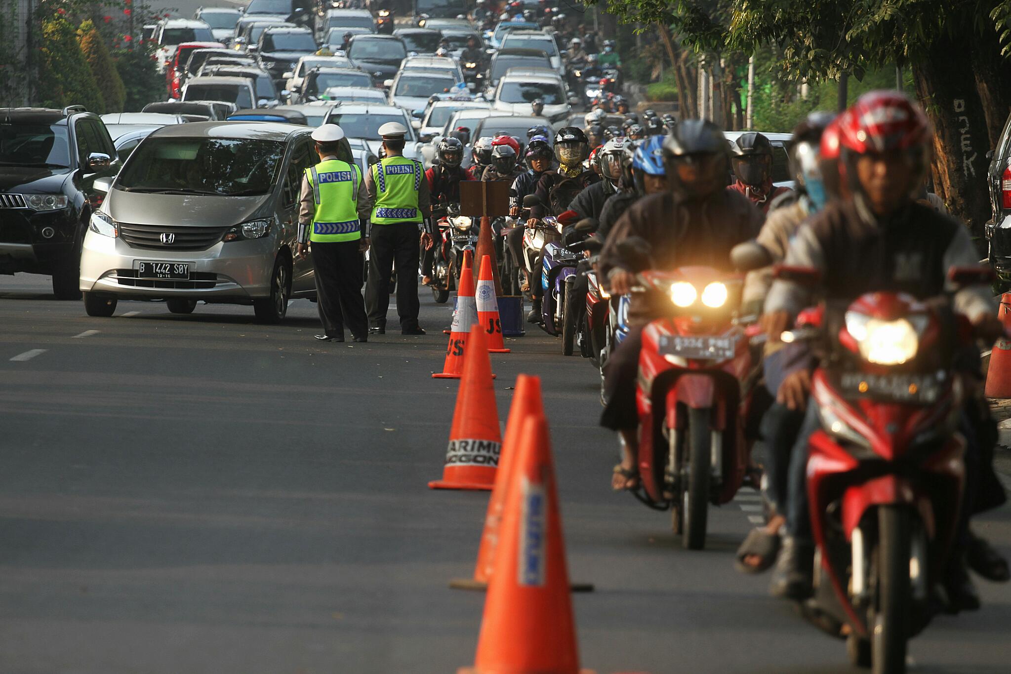 Pengendara motor menyalakan lampu di siang hari