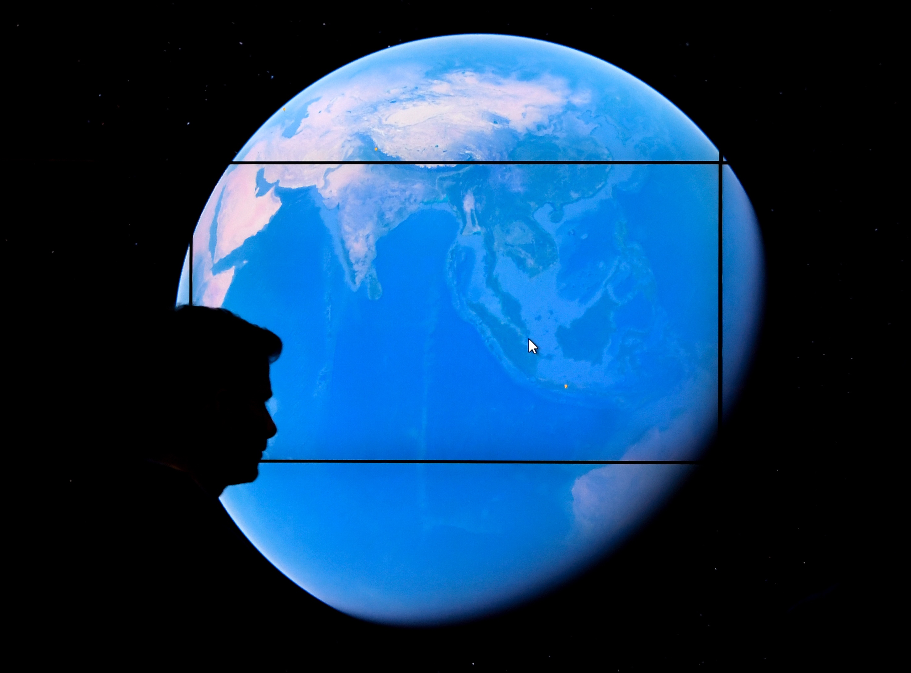 Seorang pria tengah melihat peta Google Earth di layar, di Whitney Museum, AS.