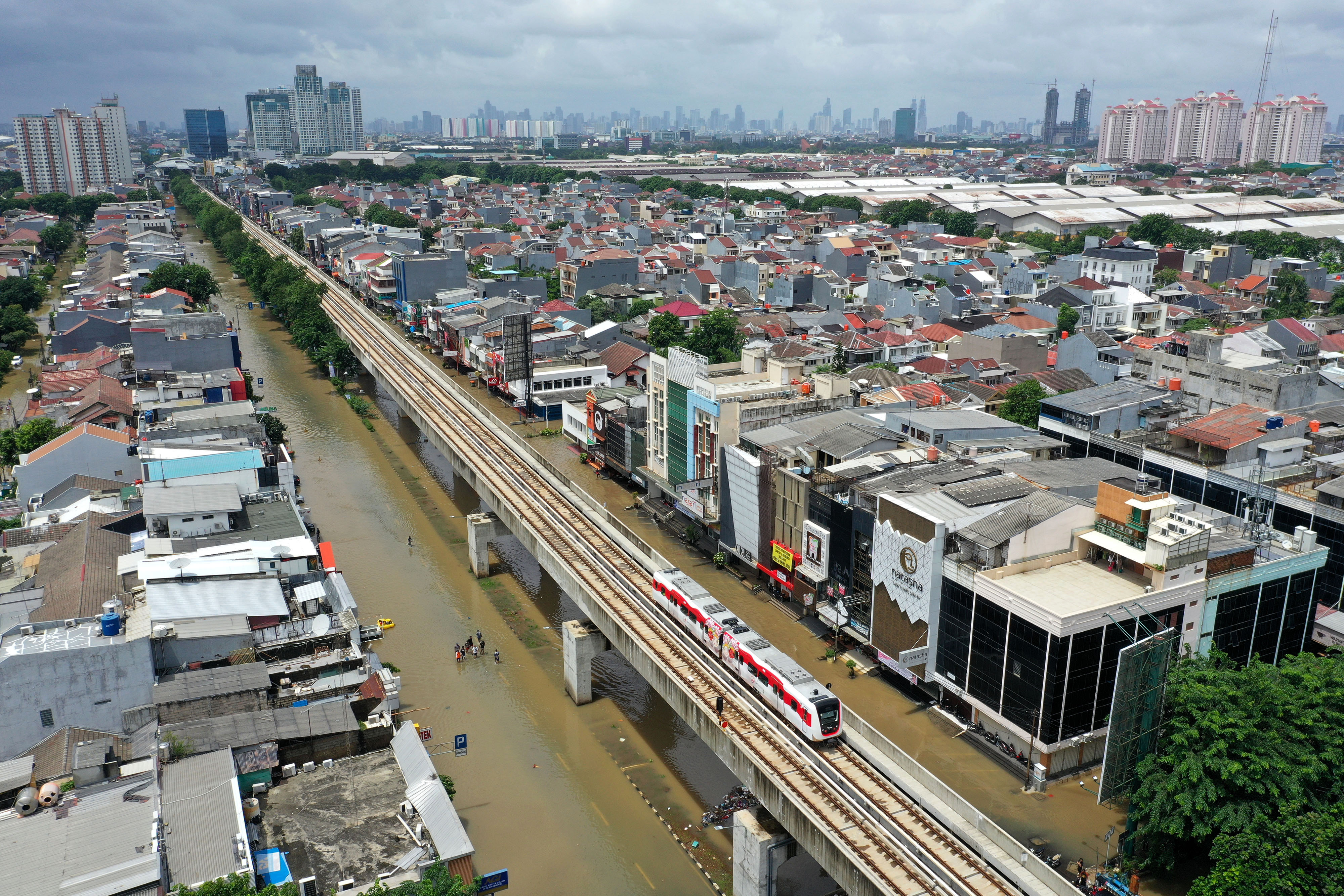 Kereta LRT melintas saat banjir merendam Jalan Boulevard Raya, Kelapa Gading, Jakarta Utara, Minggu (23/2).