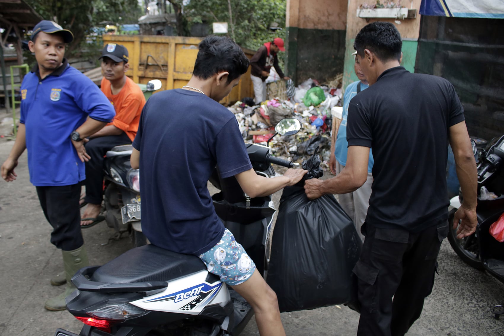 Petugas kebersihan membantu warga membuang sampah dan diam-diam memungut pungli di tempat pembuangan sampah (TPS) Pasar Tugu, Depok.