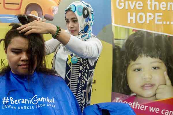 Seorang relawan Imaculata Dwivena (26) dicukur rambutnya saat aksi 