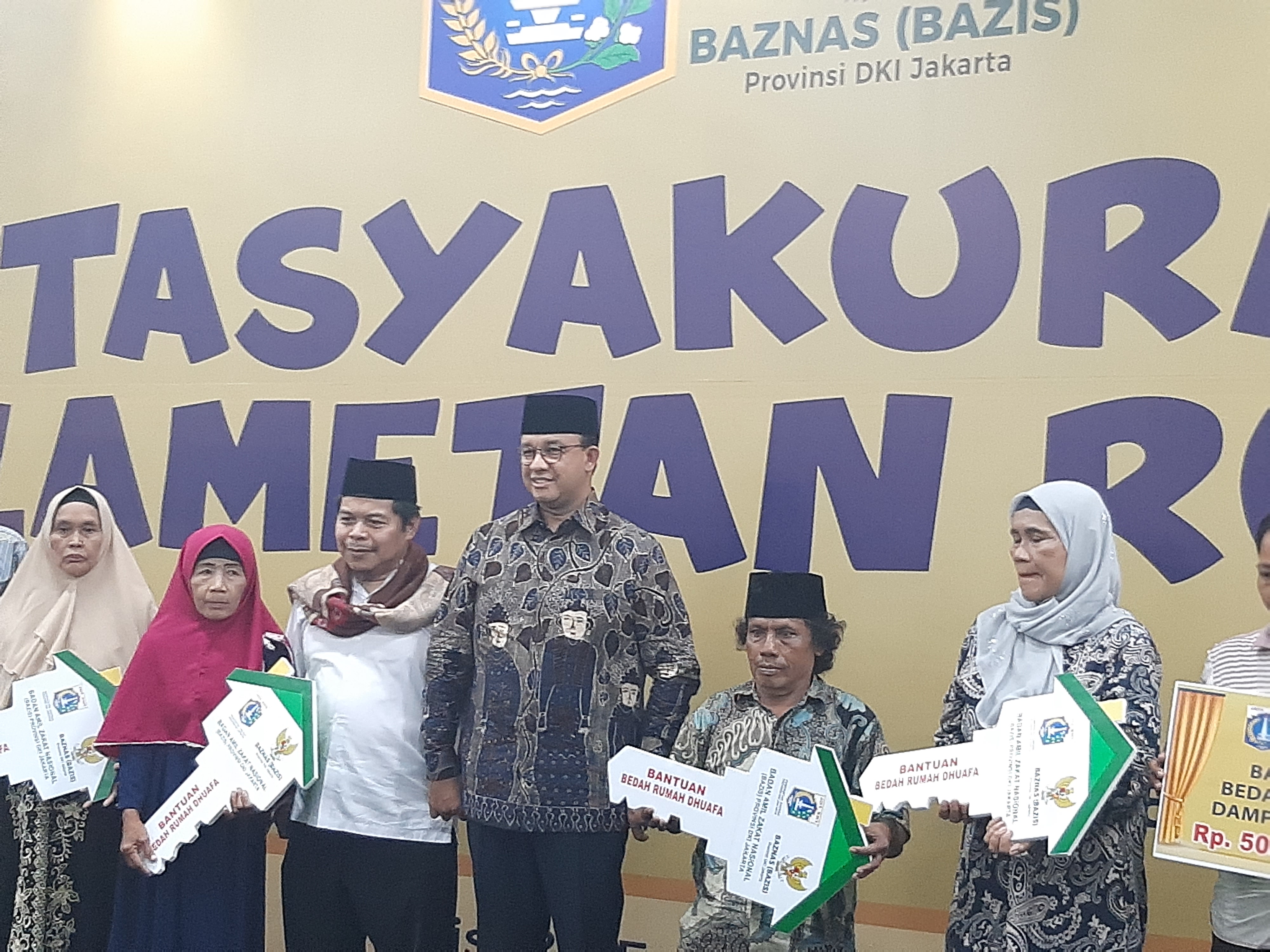 Gubernur DKI Jakarta Anies Baswedan menyerahkan kunci secara simbolis kepada penerima bantuan bedah rumah.
