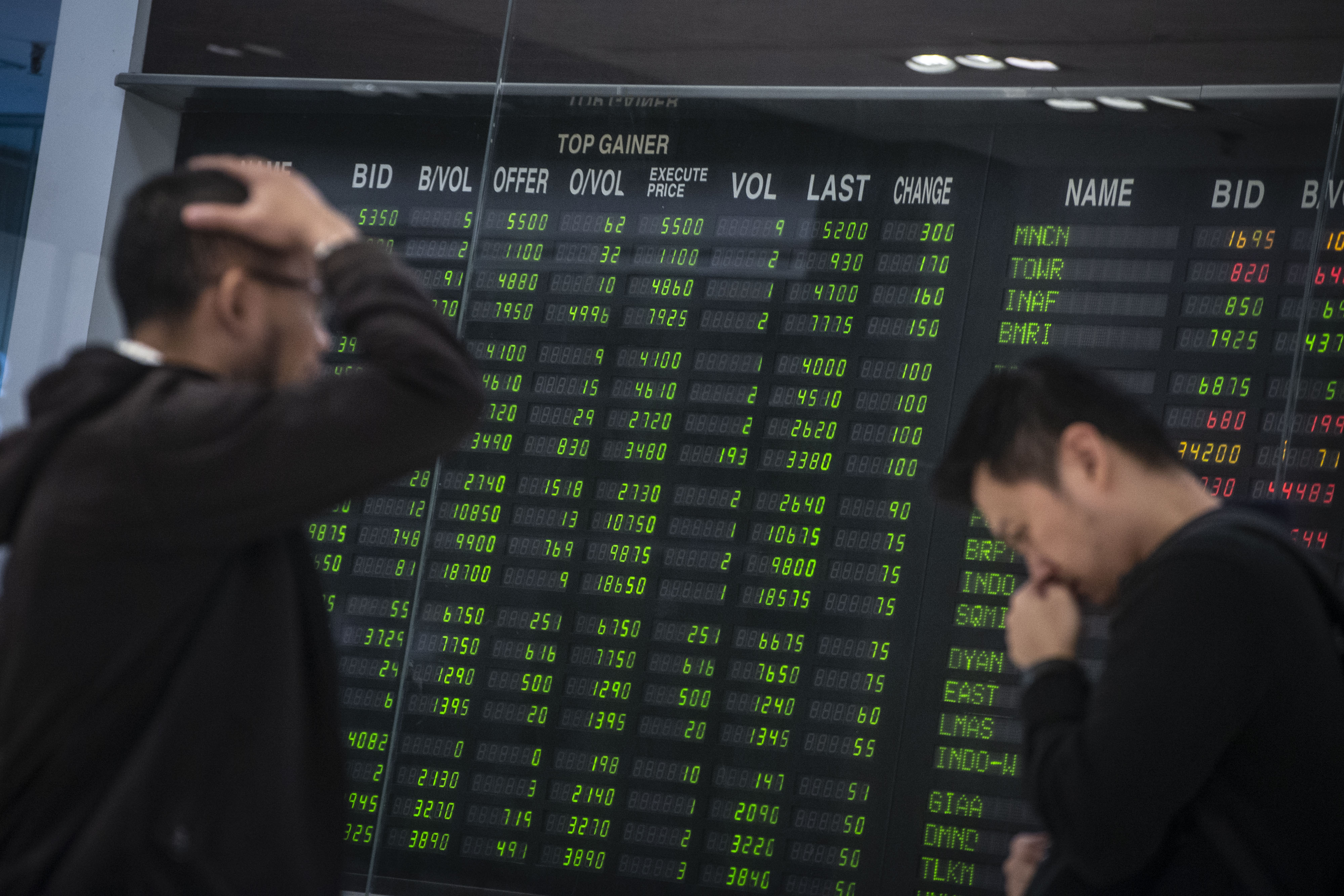 Karyawan melewati monitor pergerakan angka Indeks Harga Saham Gabungan (IHSG) di Plaza Bank Mandiri. 