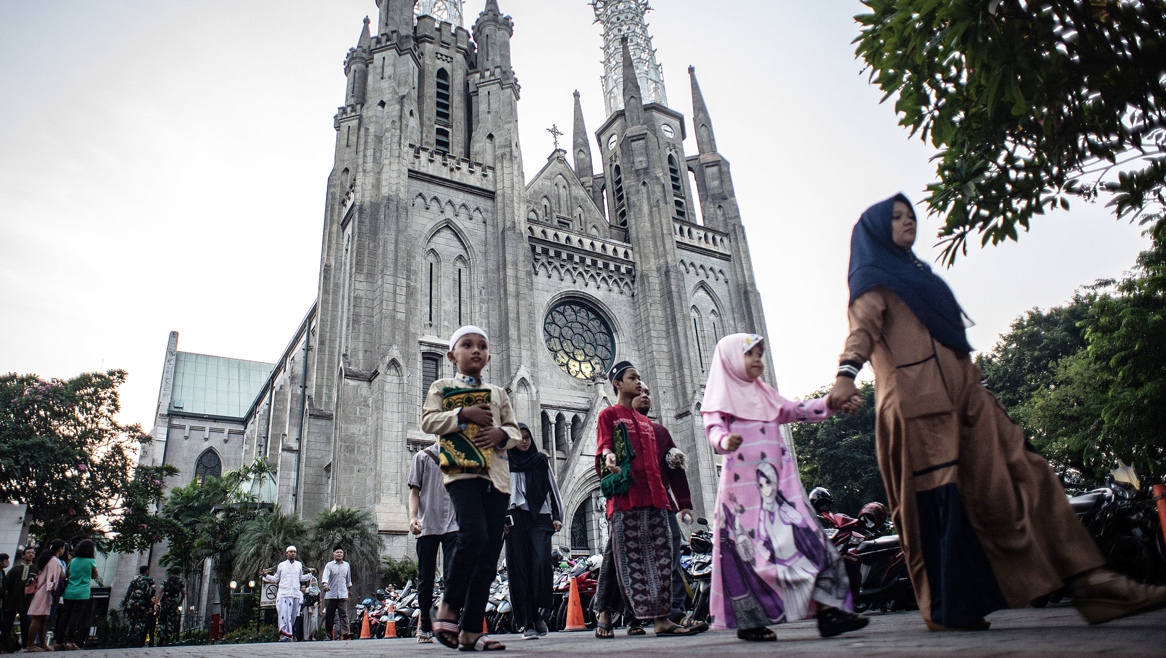 Pemeluk agam islam memarkir kendaraannya di Gereja Katedral Jakarta, lalu melaksanakan ibadah di Masjid Istiqlal.