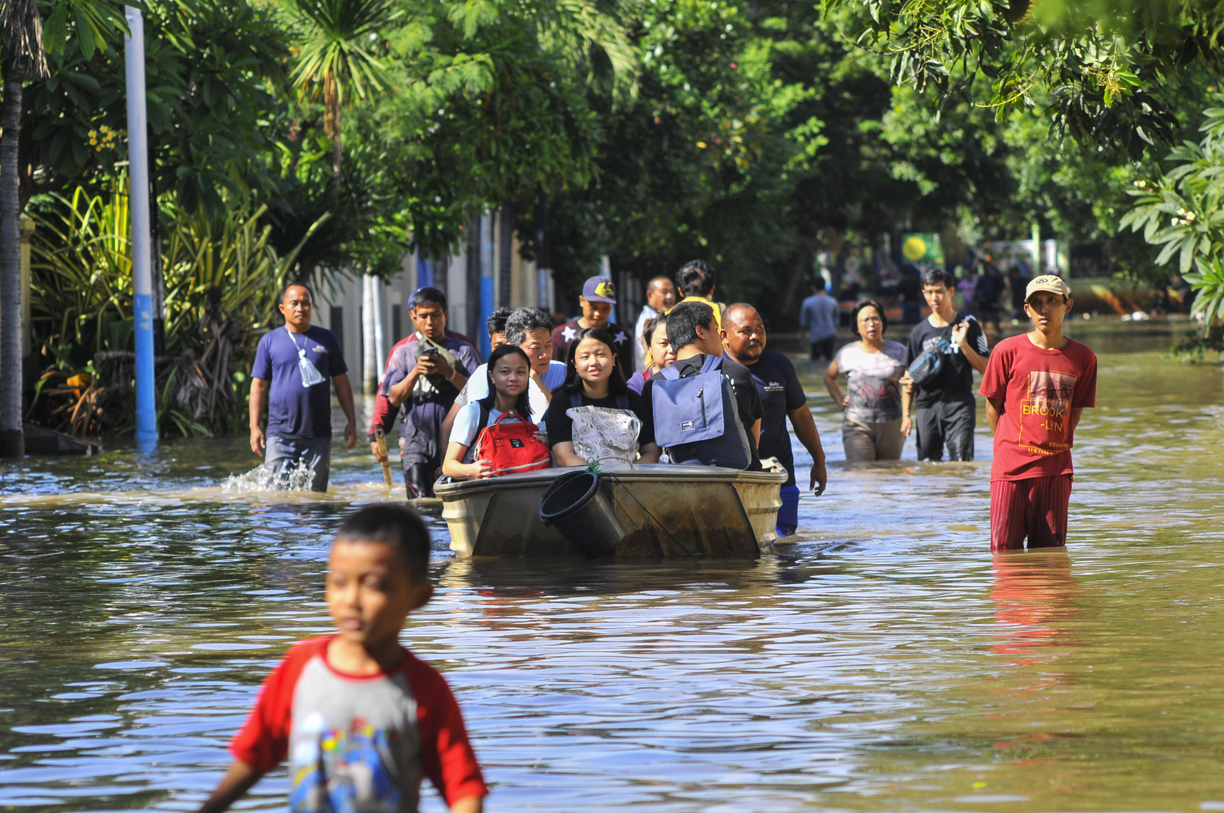 Sejumlah warga menaiki perahu saat banjir di Pulomas, Jakarta Timur, Minggu (23/2)