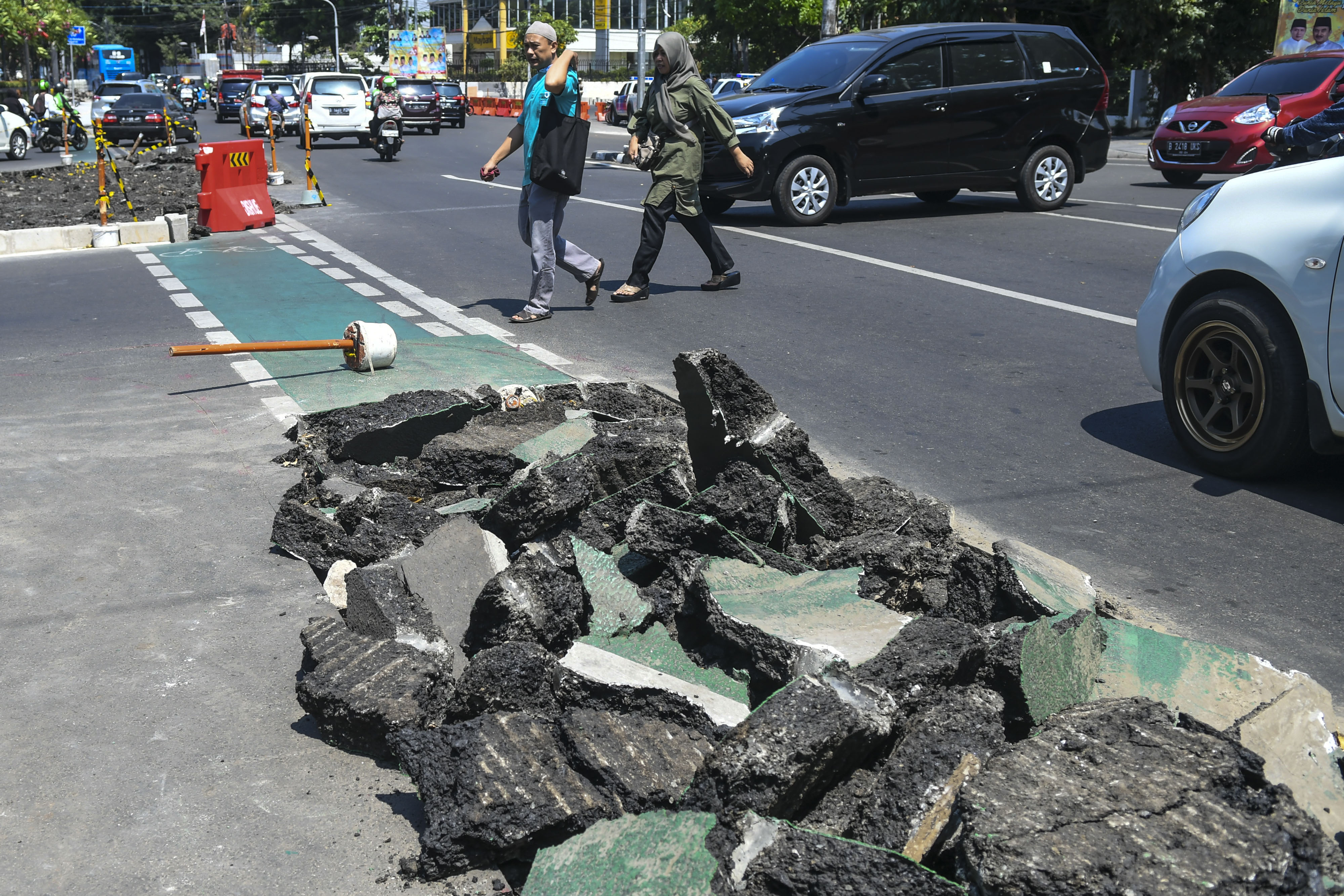  Warga melintas di samping jalur sepeda yang dibongkar di kawasan Cikini, Jakarta, beberapa waktu lalu.