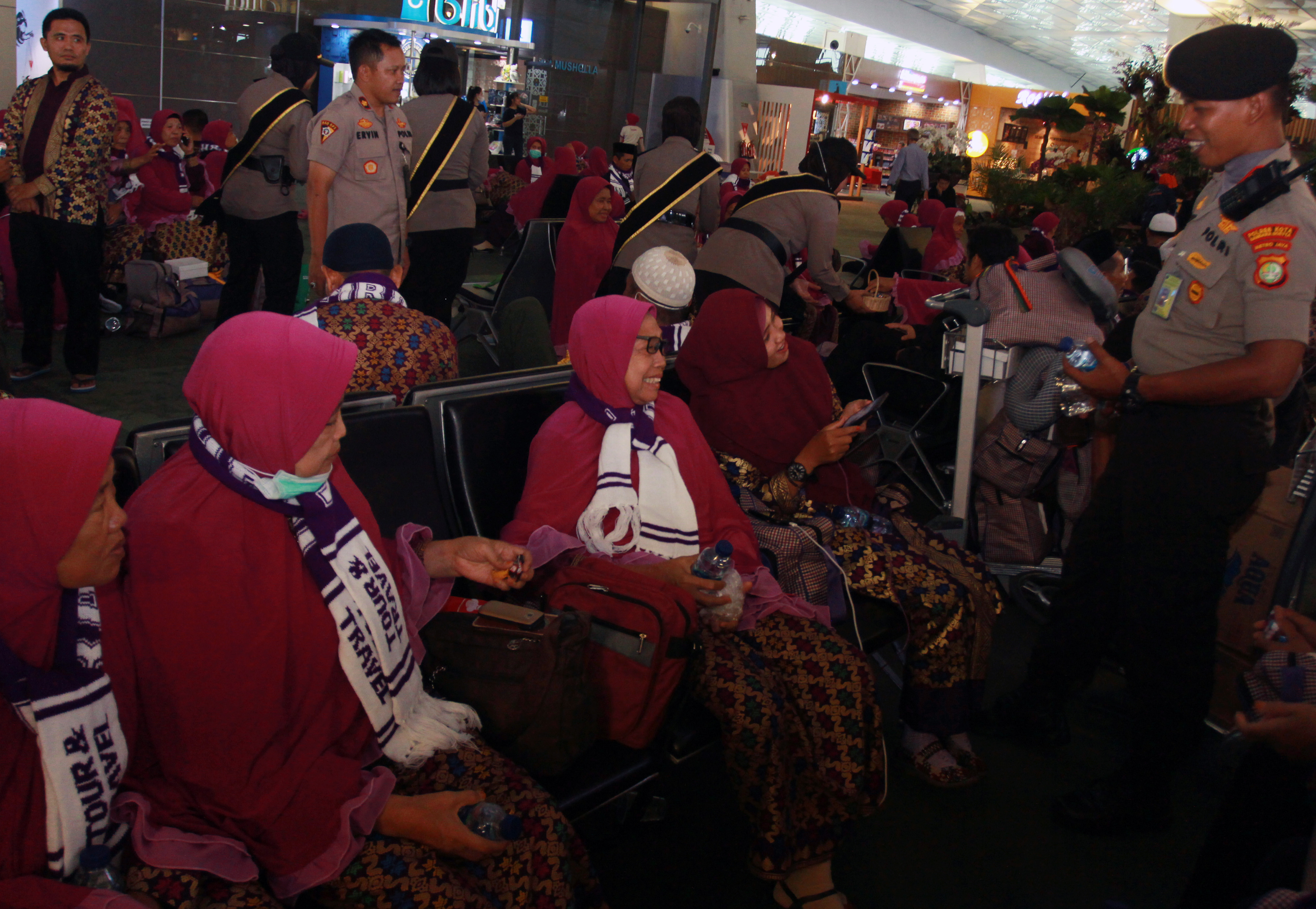 Anggota polisi Polres Bandara Soekarno Hatta menghibur calon jamaah umrah asal Lombok yang gagal berangkat ke Tanah Suci.