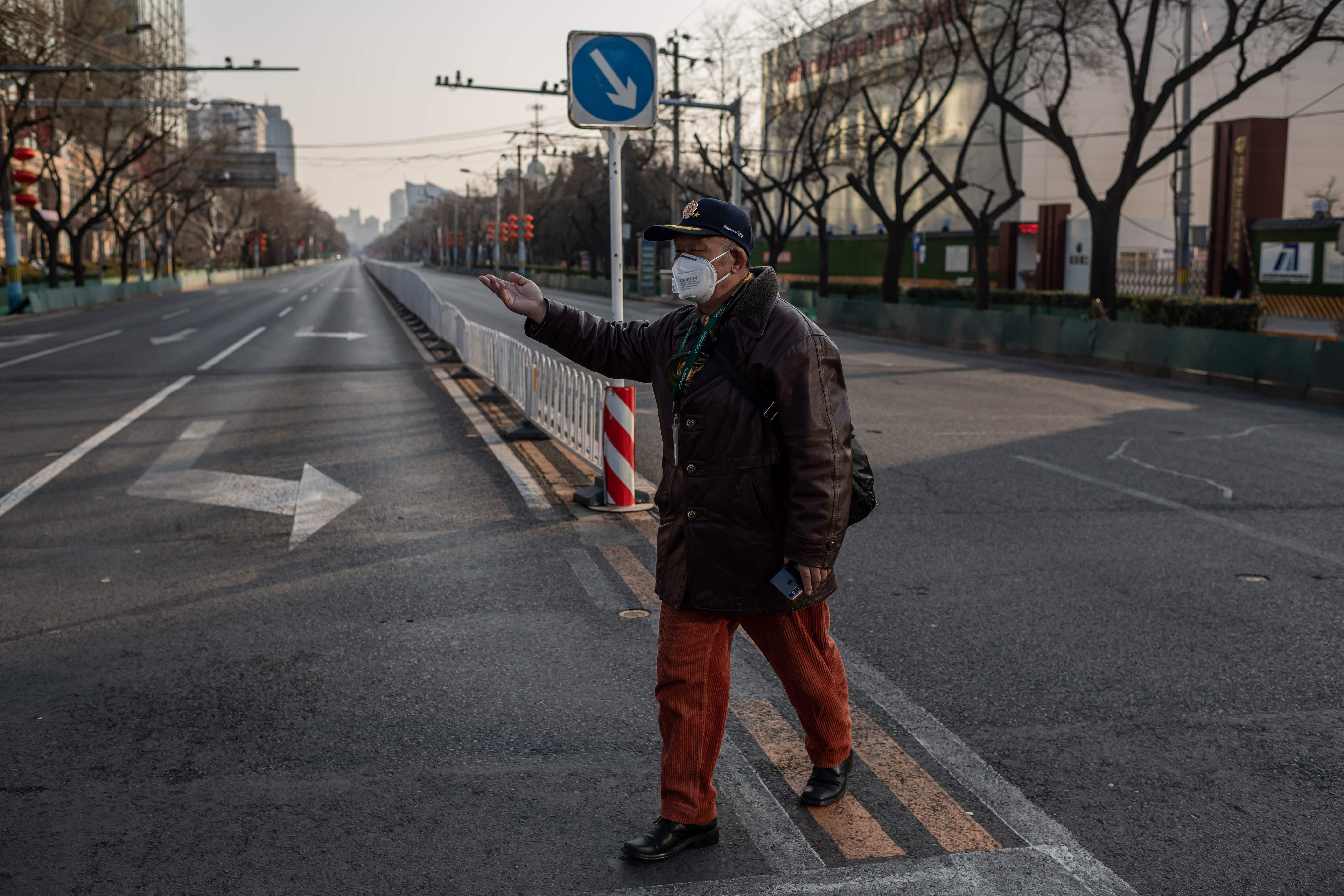 Seorang pria mengenakan masker menyeberang jalan di Beijing, Tiongkok