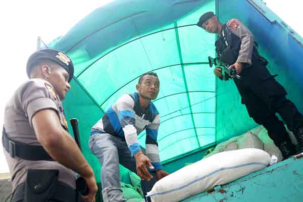 Pekerja mengangkat karung berisi minuman keras jenis Cap Tikus yang dimasukkan dalam plastik di Mapolda Gorontalo.