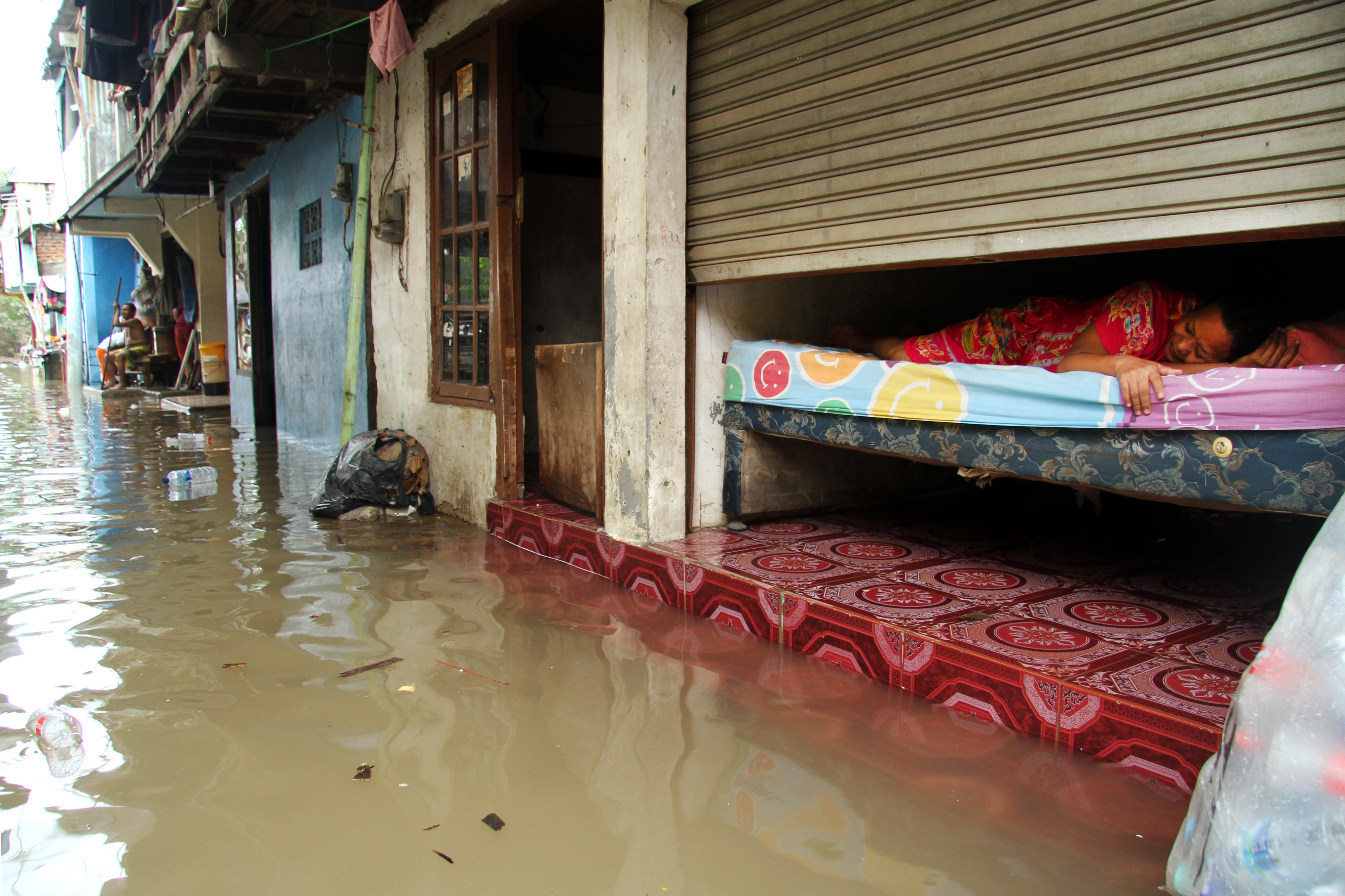 Warga beraktivitas di kawasan permukiman penduduk yang tergenang banjir, di Kampung Petukangan, Cakung, Jakarta, hari ini.