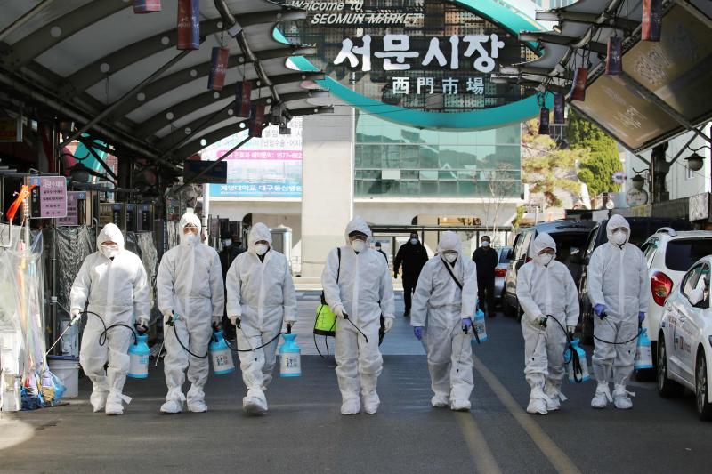 Petugas mengenakan pakaian berpelindung saat menyemprotkan disinfektan di Daegu
