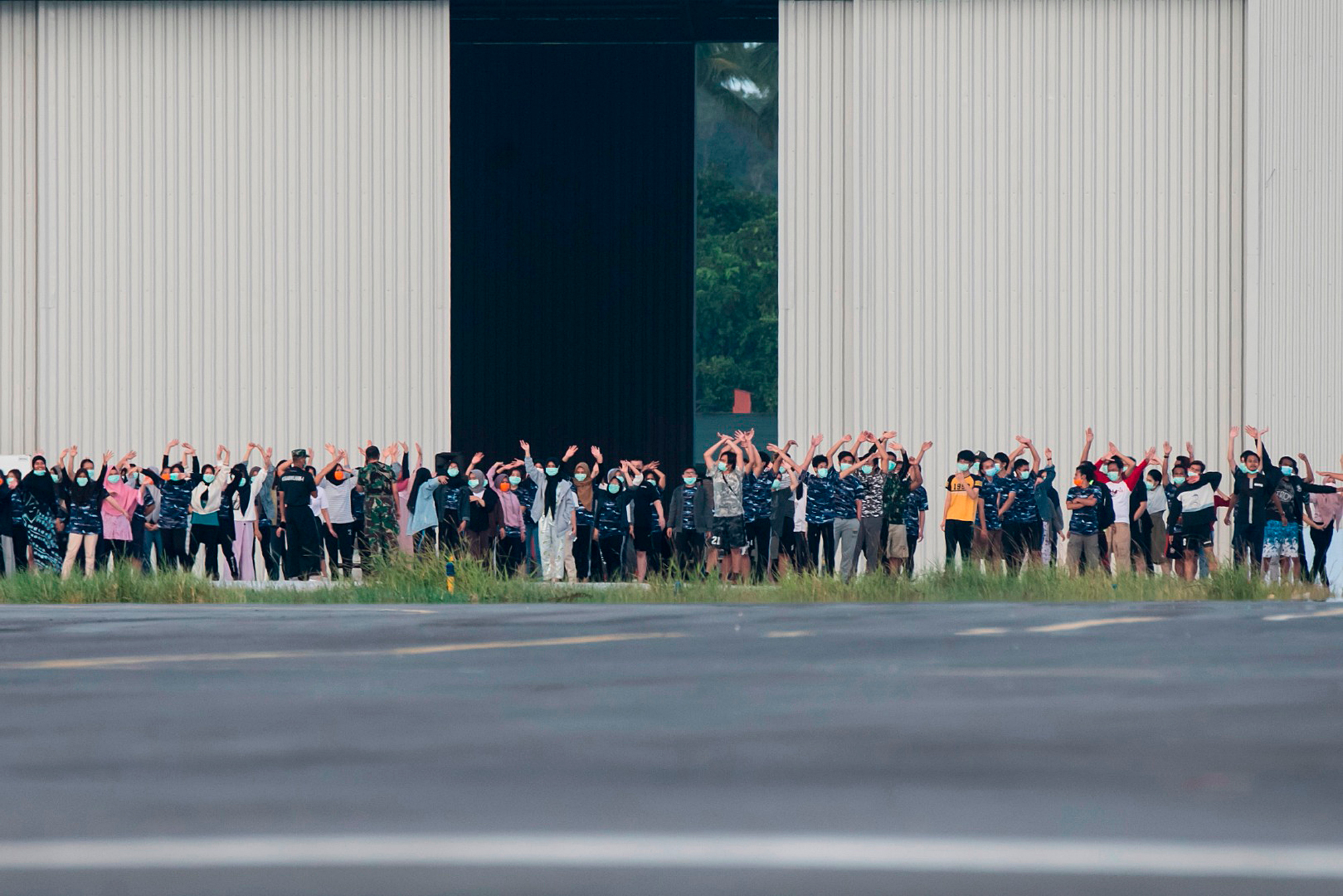 Sejumlah Warga Negara Indonesia (WNI) yang dievakuasi dari Wuhan, Hubei, China melambaikan tangan kearah media saat akan melakukan senam.
