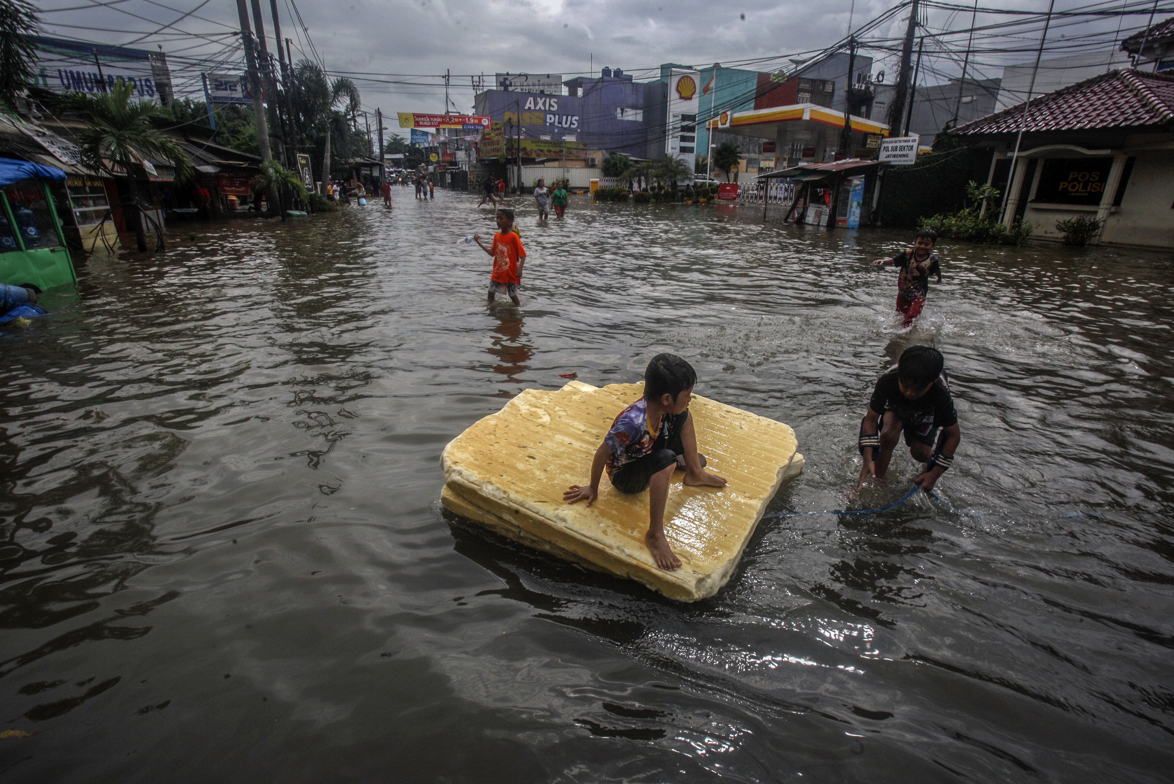 Sejumlah anak bermain di Jalan Jatibening Raya, Bekasi, yang terendam banjir akibat guyuran hujan deras, Selasa (25/2).