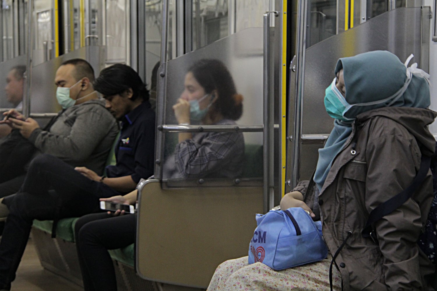 Penumpang Commuter Line menggunakan masker