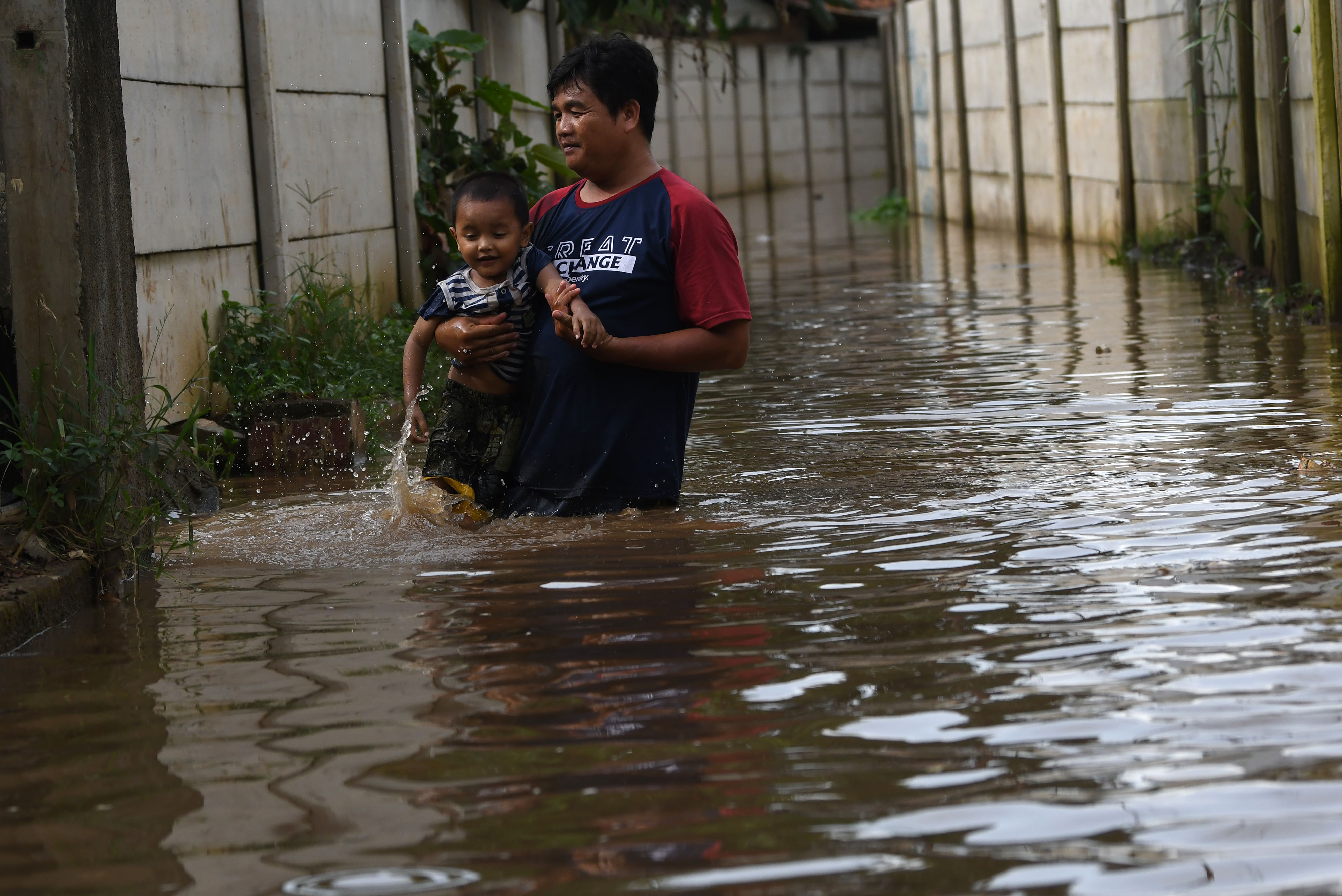 Warga menyusuri jalan perkampungan yang tergenang banjir luapan air Sungai Ciliwung di Cawang, Jakarta.