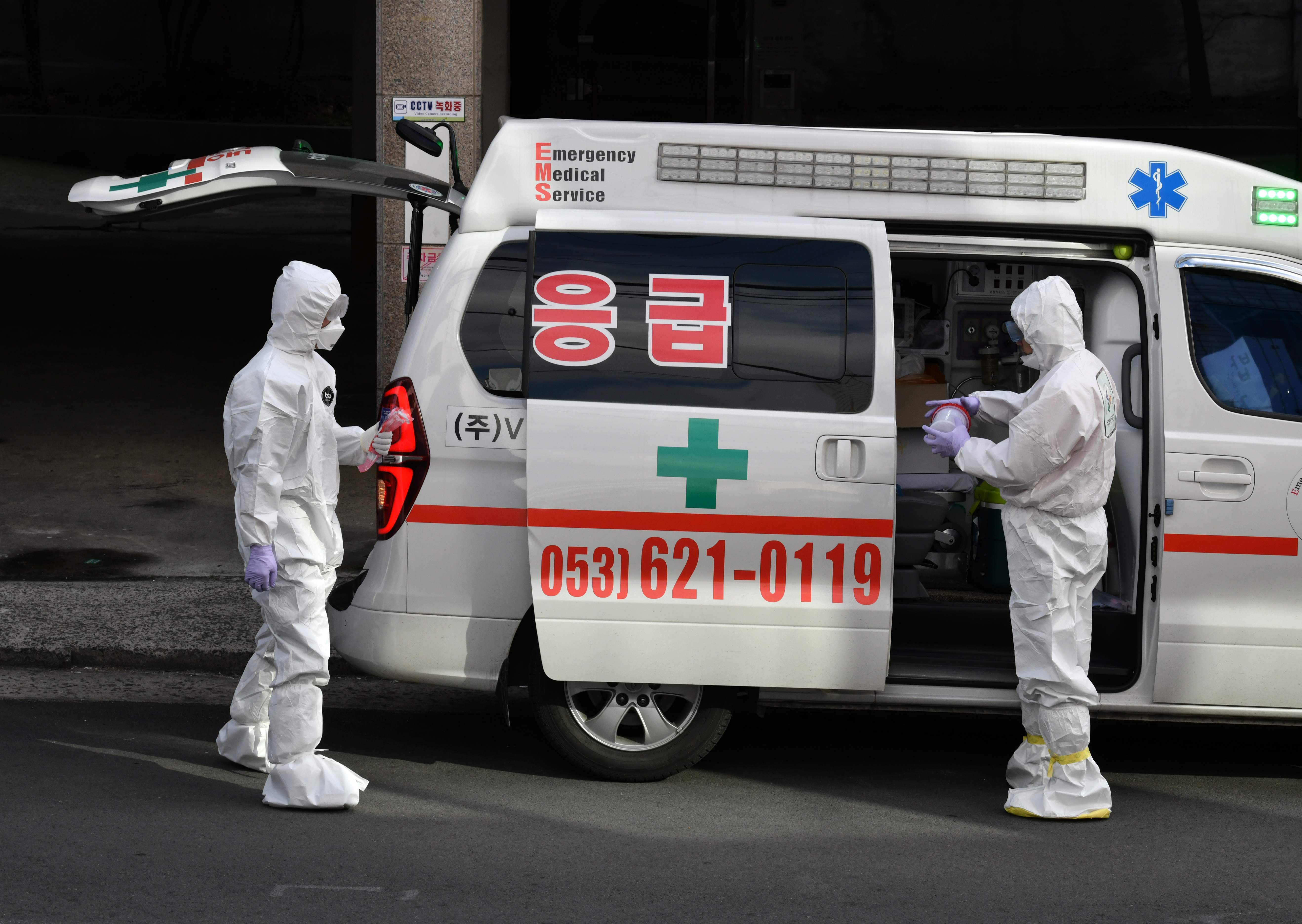 Petugas medis berpakaian pelindung membawa sampel dari suspek virus korona di sebuah perumahan di Daegu, Korsel.