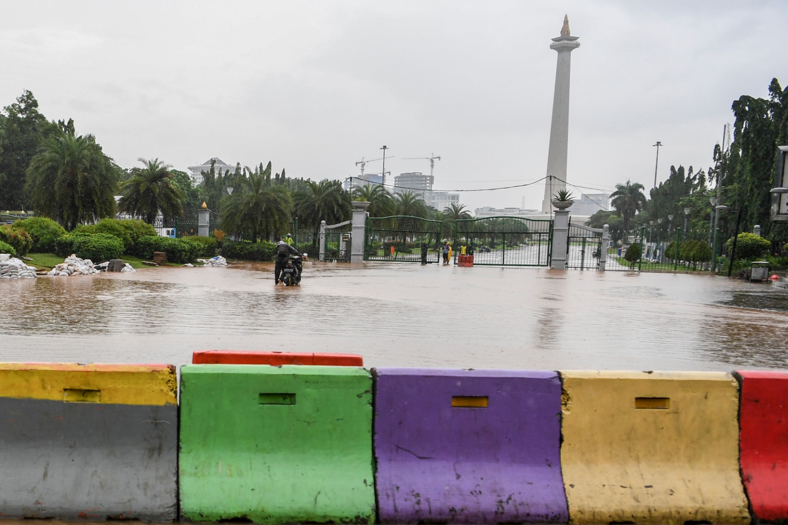 Warga mendorong motor melintasi banjir di kawasan Monas, Jalan Medan Merdeka Barat, Jakarta, Minggu (2/2/2020). 