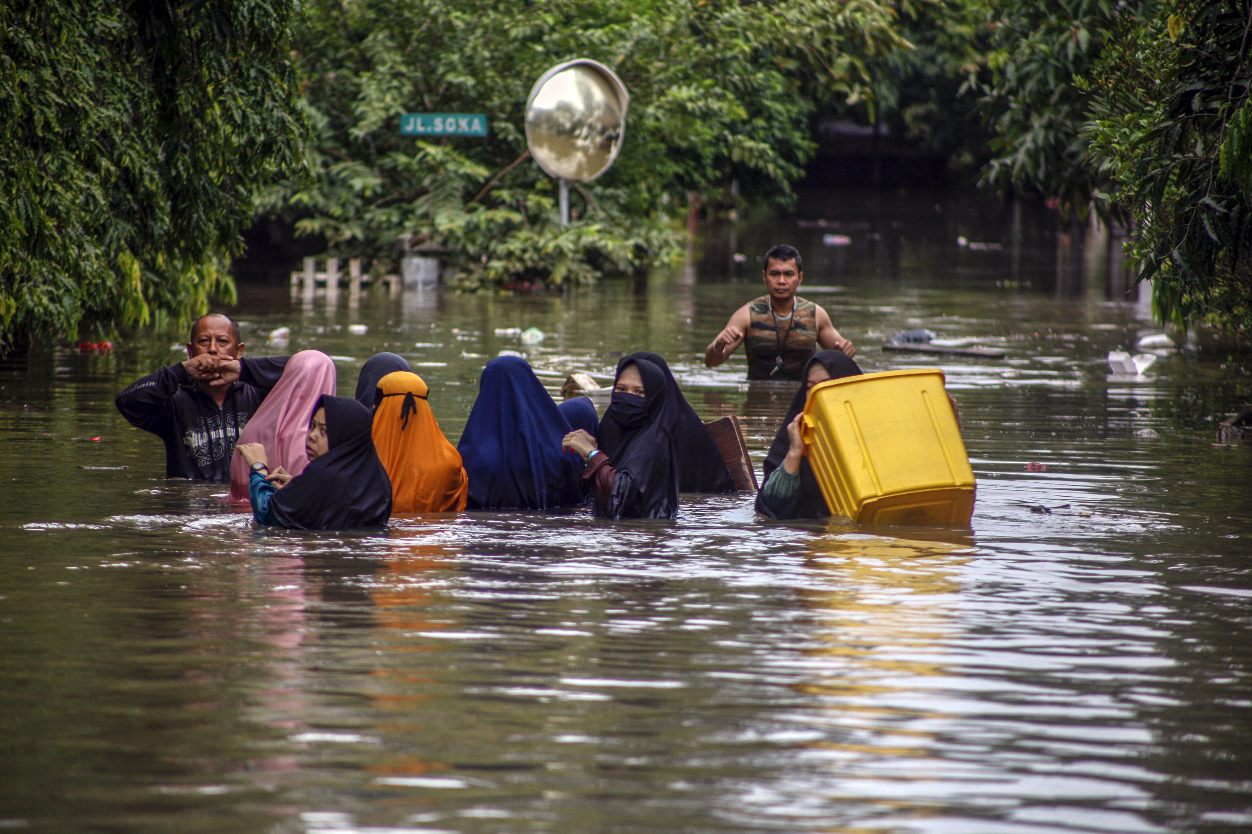Sejumlah warga melintasi genangan banjir di Perumahan Jatibening Permai, Bekasi, Jawa Barat, Selasa (25/2).