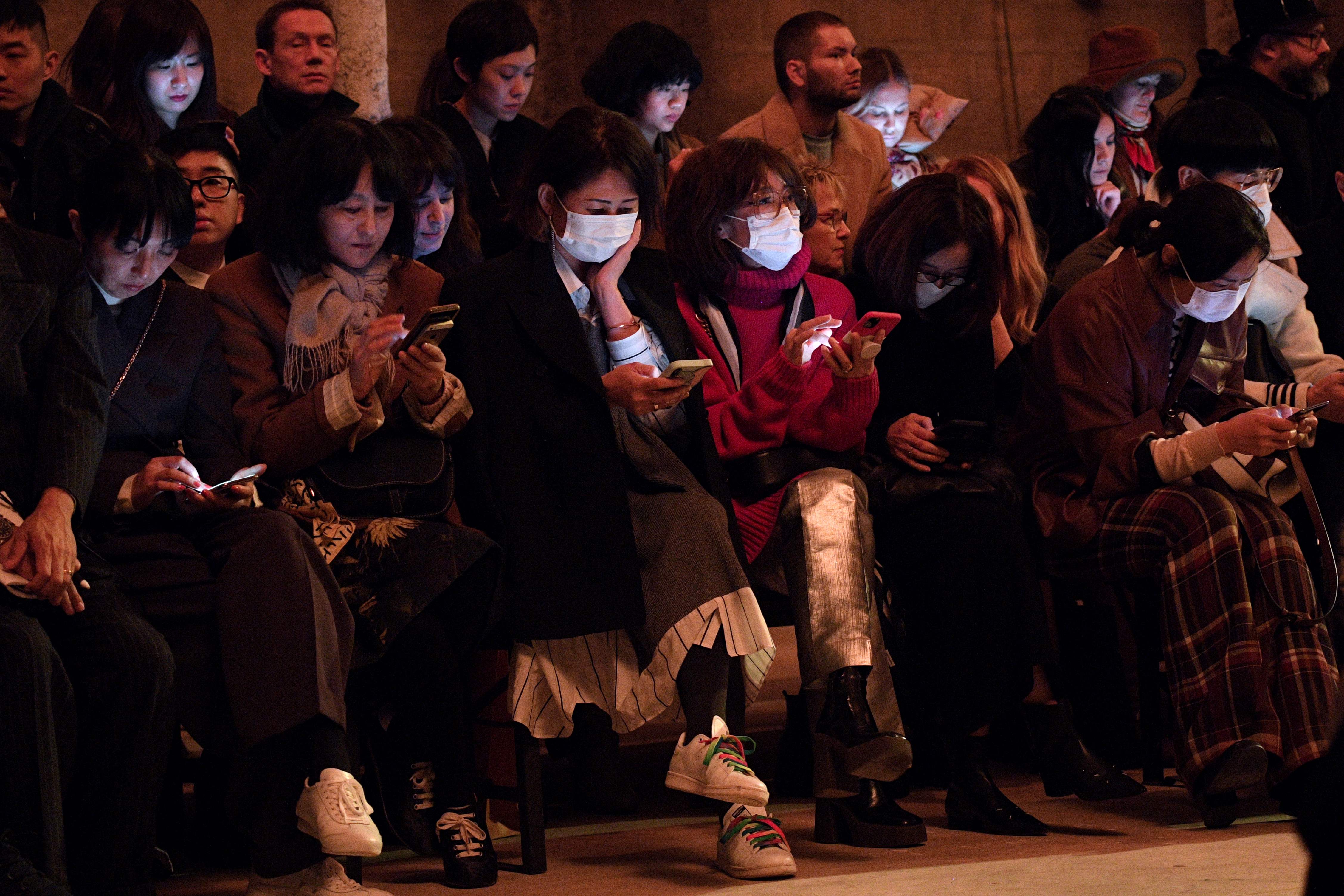 Sejumlah orang mengenakan masker saat menghadiri sebuah pagelaran busana di Paris, Prancis.