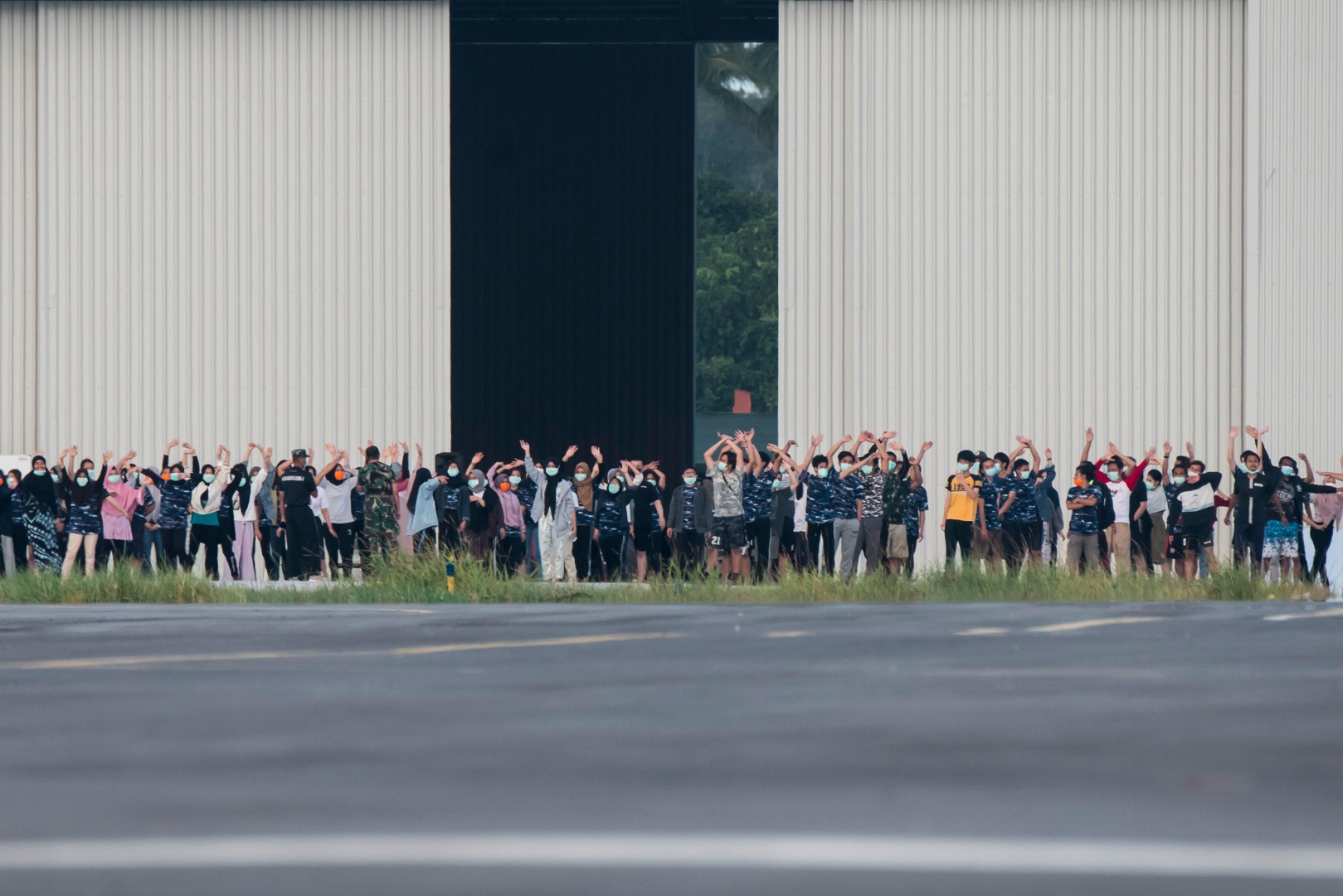 Sejumlah Warga Negara Indonesia (WNI) yang dievakuasi dari Wuhan, Hubei, Tiongkok melambaikan tangan ke arah media, Jumat (14/2).
